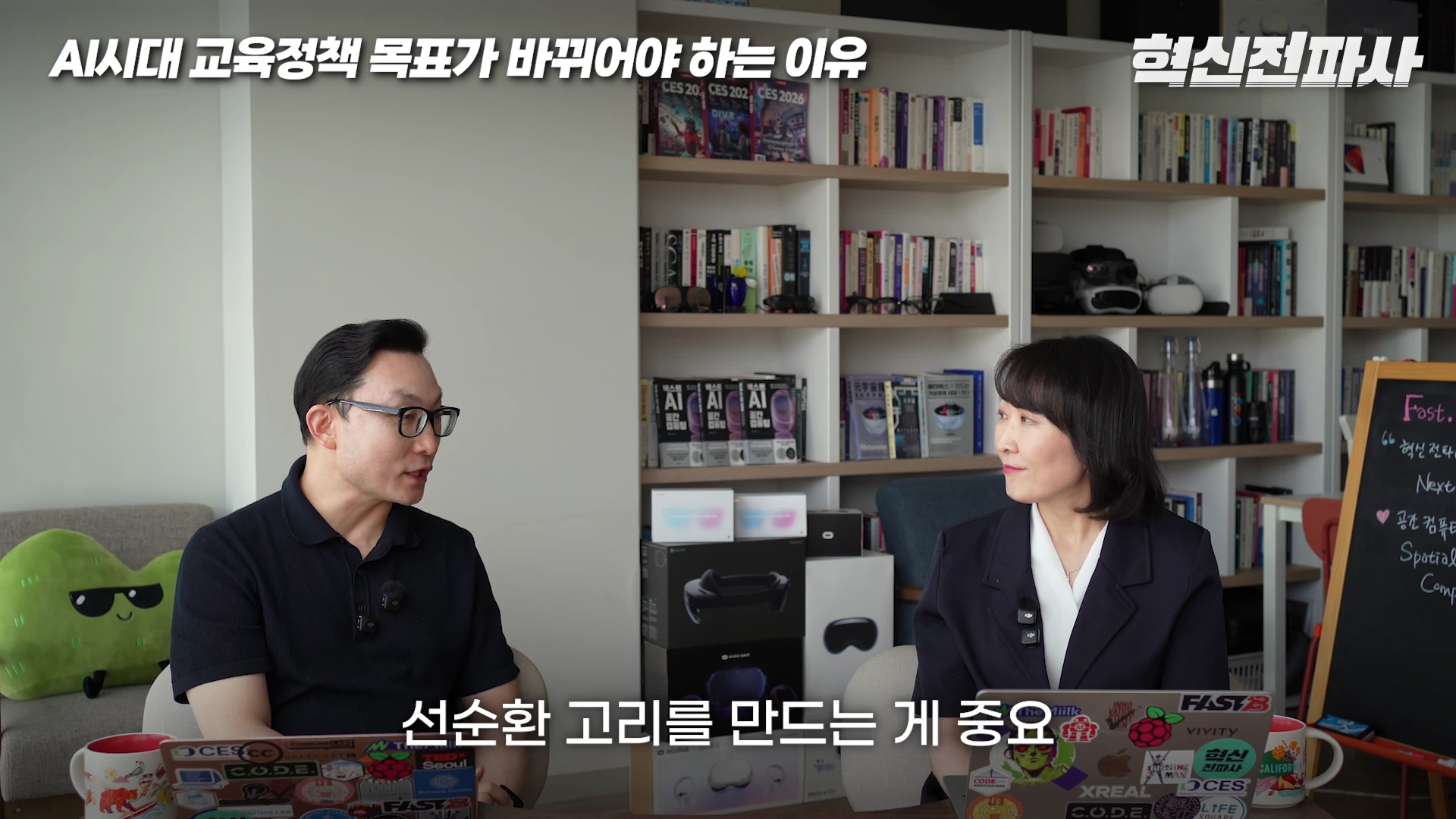 두 명의 출연자가 서재를 배경으로 마주 앉아 대화를 나누고 있는 스튜디오 장면