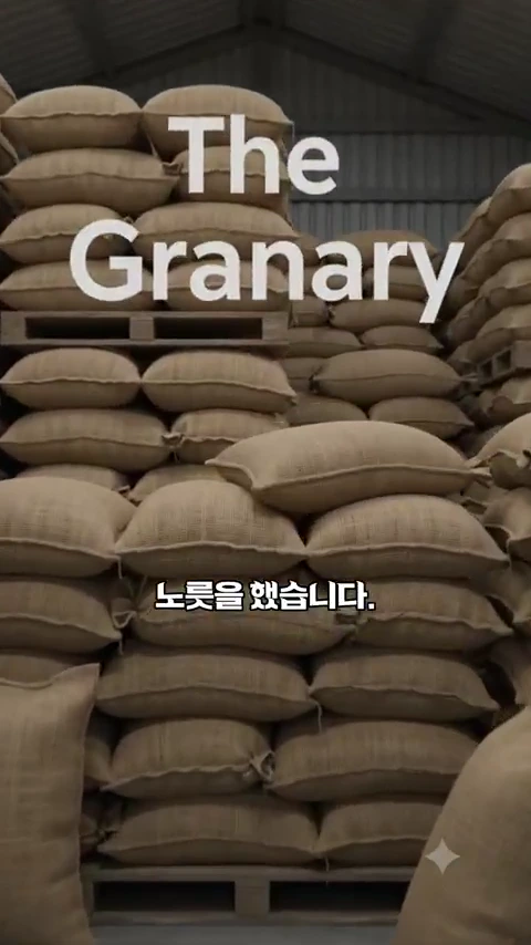 창고에 가득 쌓여 있는 마대 자루들 위로 The Granary라는 영문 문구와 함께 한글 자막이 겹쳐져 있는 영상 화면.