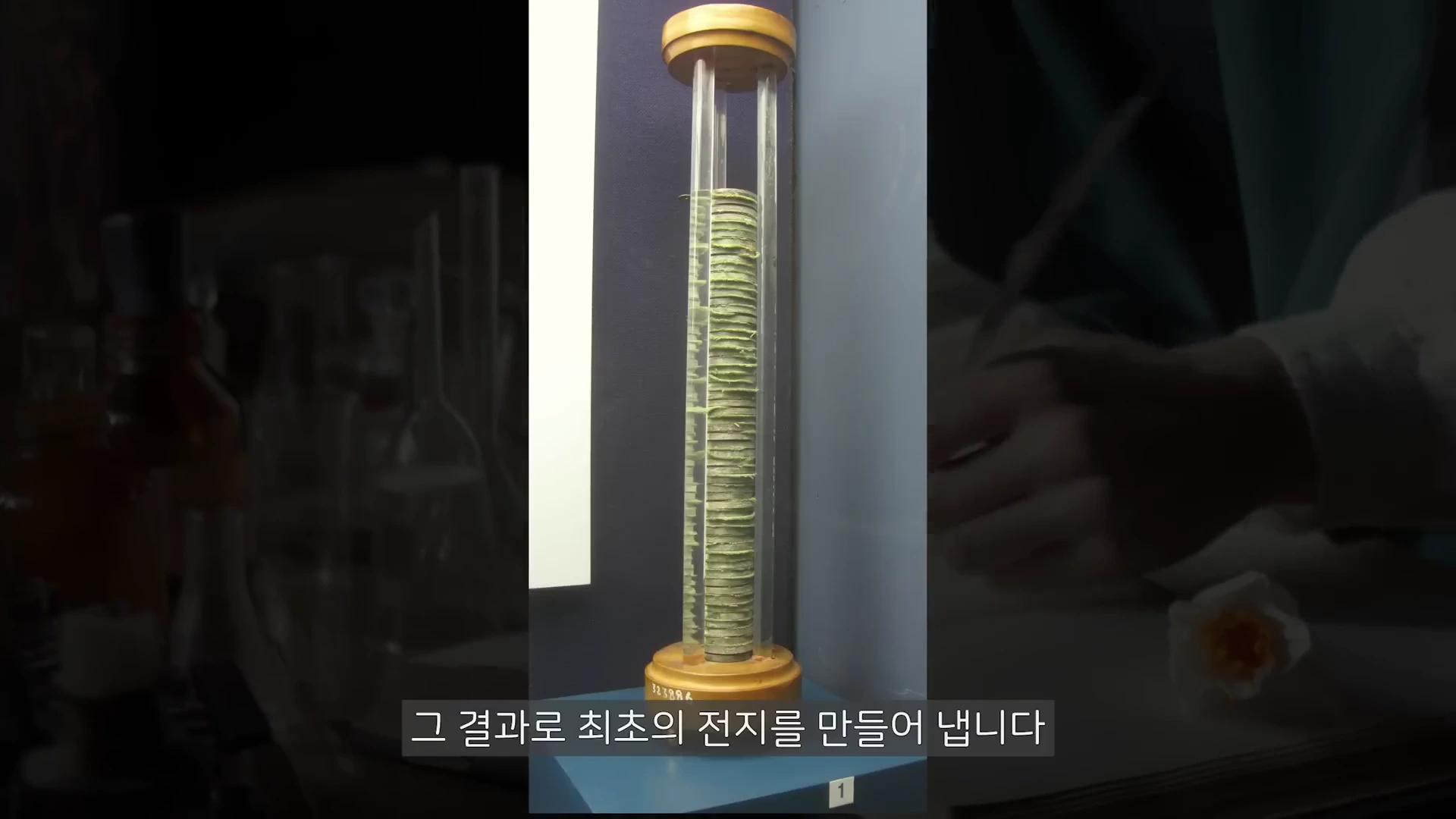 원통형 구조 안에 서로 다른 금속판들이 층층이 쌓여 있는 초기 전지 모형이 전시되어 있다.