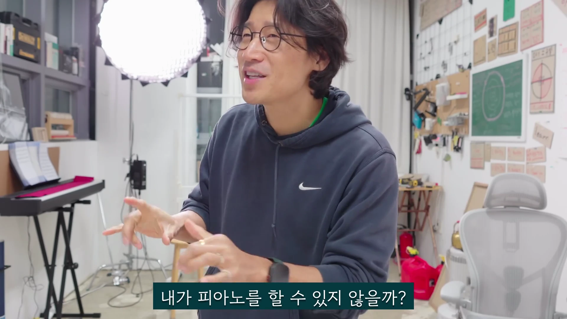 안경을 쓴 남성이 작업실에서 손짓하며 이야기를 나누고 있고, 화면 하단에는 '내가 피아노를 할 수 있지 않을까?'라는 자막이 표시되어 있습니다.
