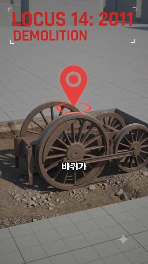 철로 위에 놓인 기차 바퀴와 프레임이 그래픽으로 묘사되어 있으며, 그 위에 붉은색 위치 표시 아이콘과 'LOCUS 14: 2011 DEMOLITION'이라는 영문 텍스트, 그리고 '바퀴가'라는 한글 자막이 함께 표시된 화면.