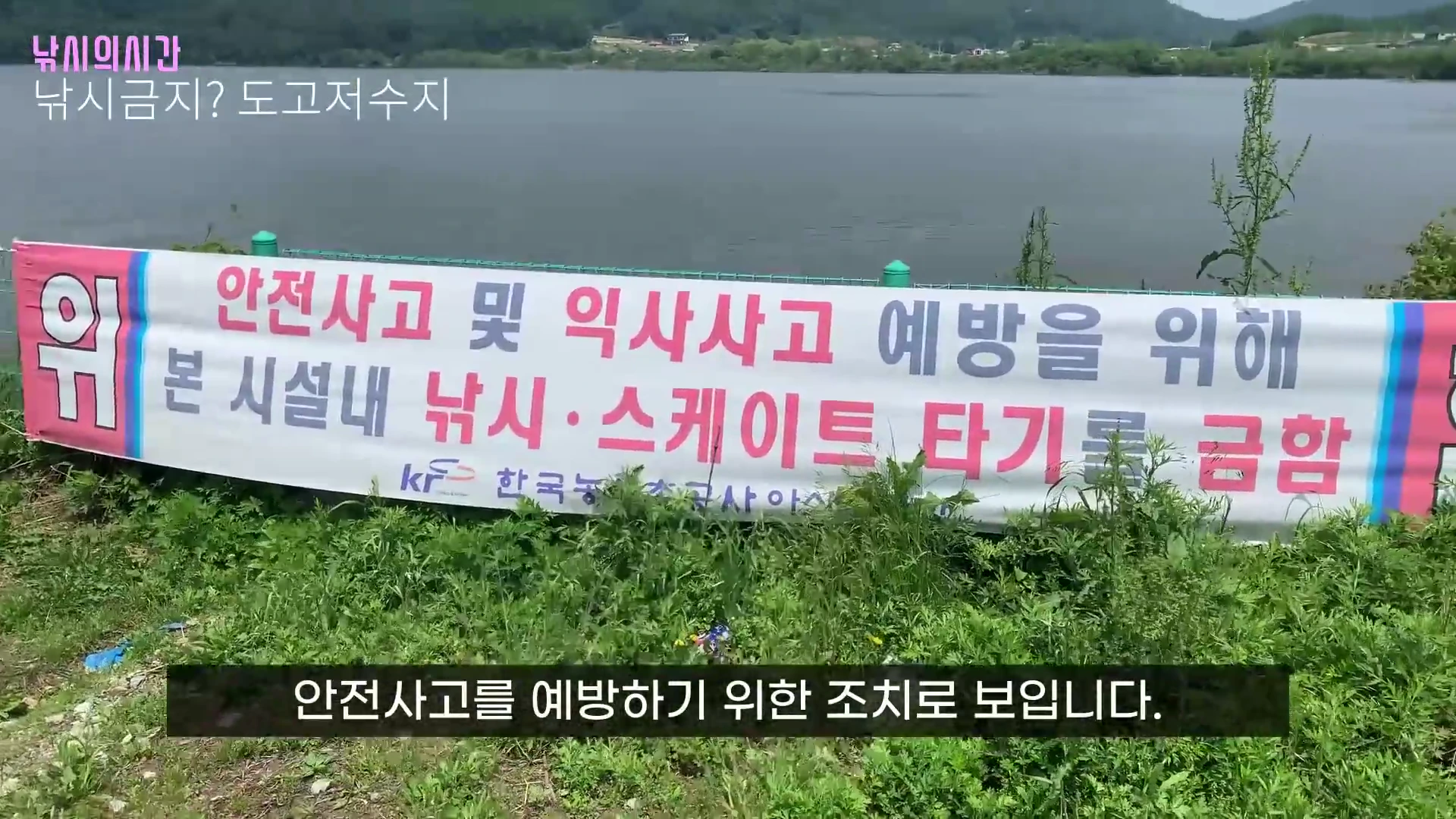저수지 연안에 설치된 낚시 금지 안내 현수막과 그 뒤로 보이는 저수지 풍경