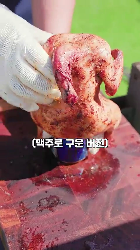 흰색 면장갑을 낀 손이 맥주캔 위에 꽂혀 노릇하게 구워진 통닭을 들어 올리고 있으며, 화면 하단에는 '(맥주로 구운 버전)'이라는 흰색 자막이 표시되어 있다.