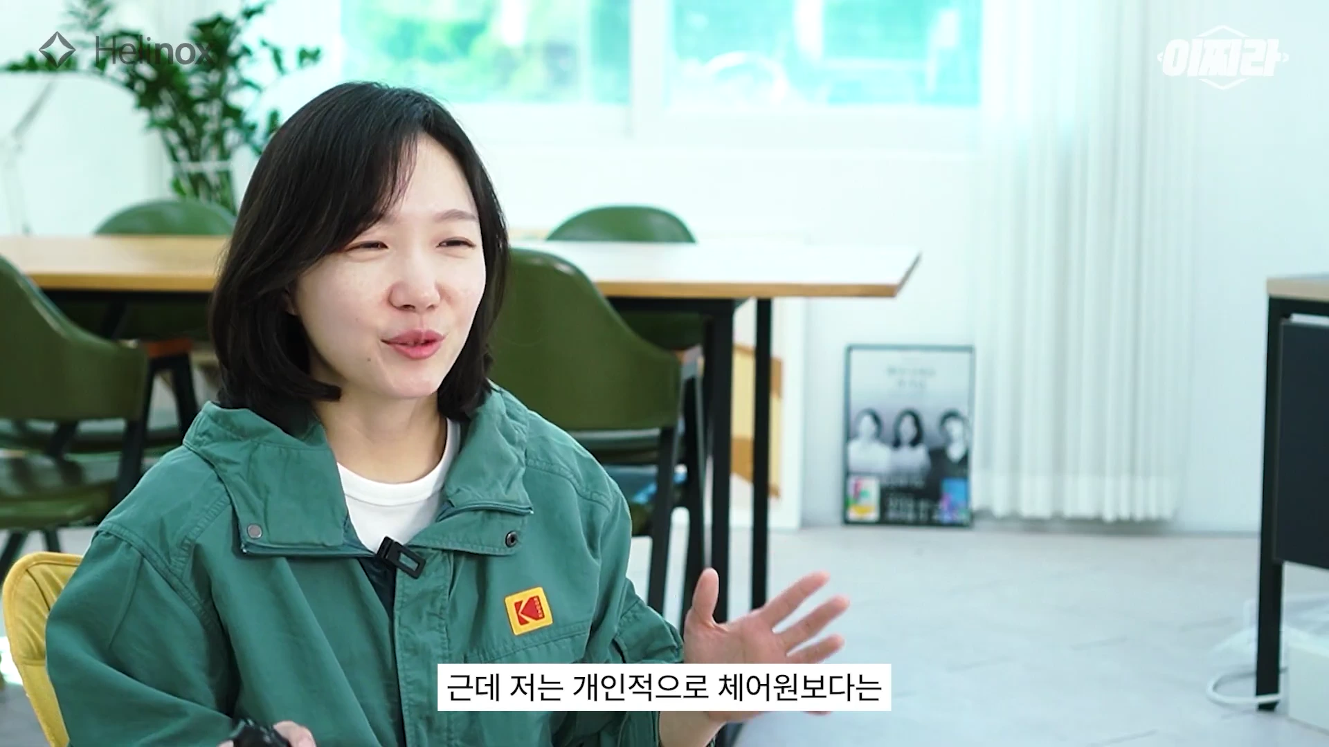 단발머리를 한 여성 화자가 밝은 실내 공간에서 손짓을 섞어가며 이야기를 나누고 있다.