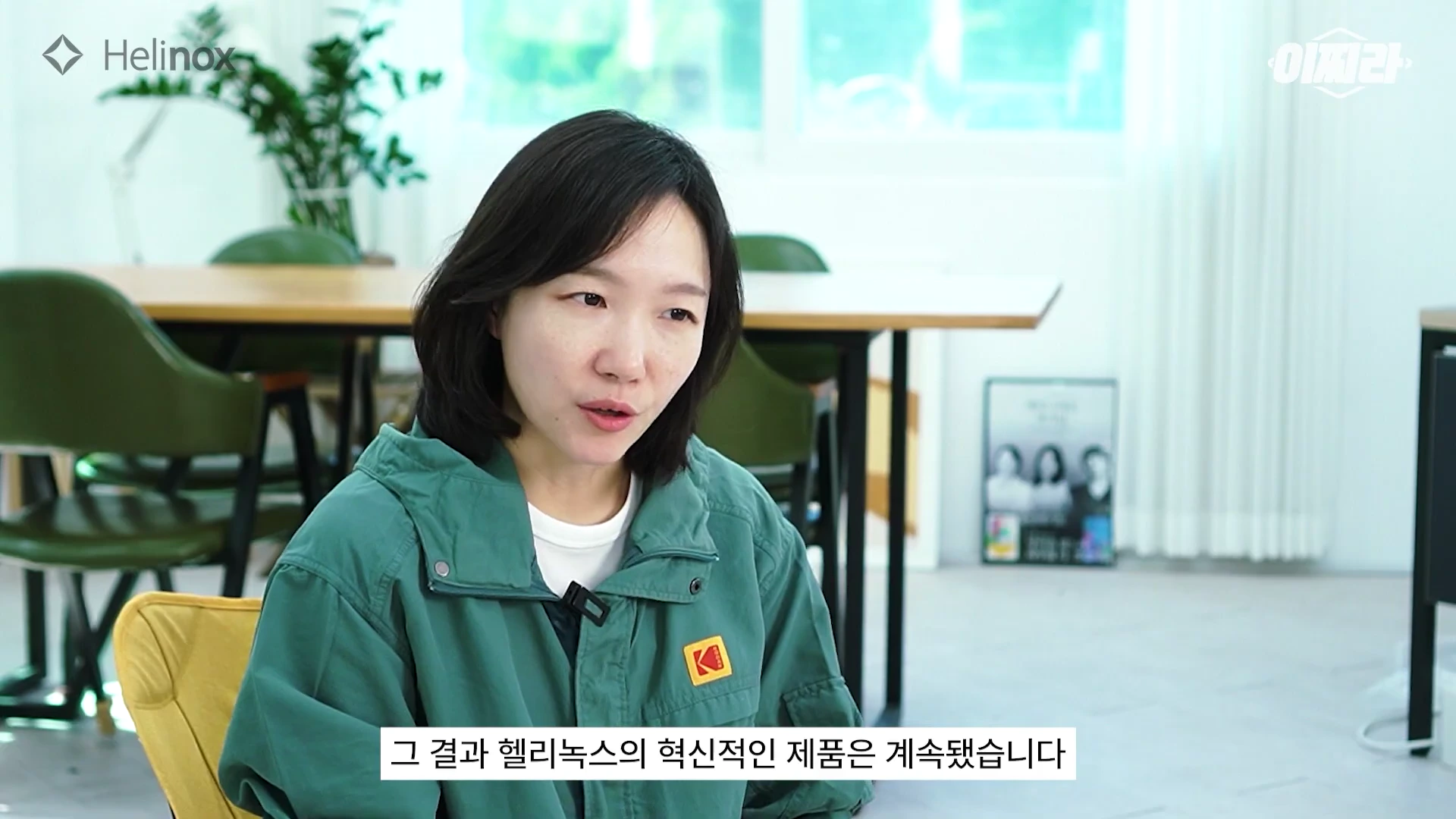 실내에서 초록색 재킷을 입은 단발머리 여성이 인터뷰하고 있는 모습