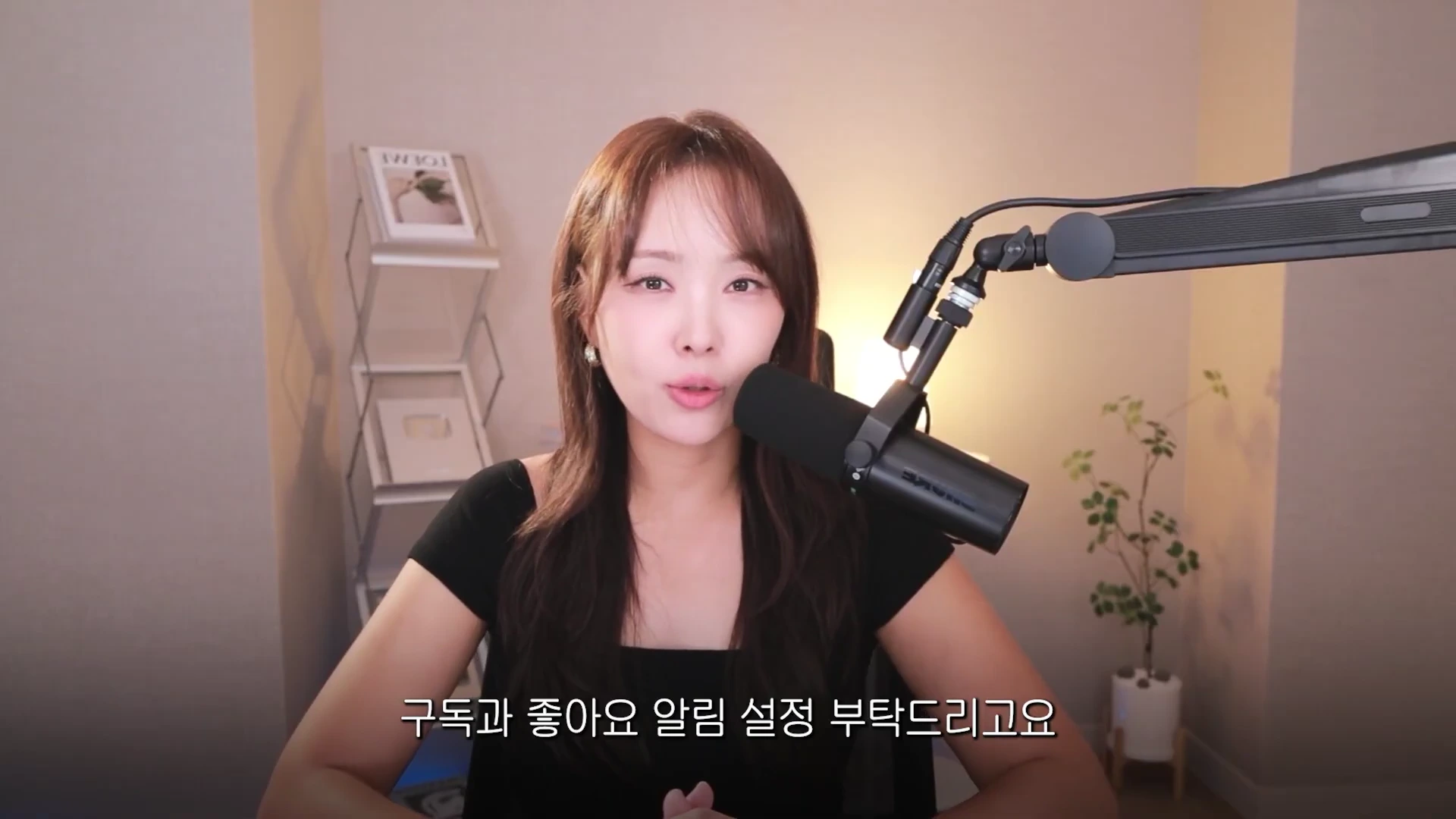 스튜디오 마이크 앞에 앉아 정면을 바라보며 이야기하는 여성의 상반신 모습