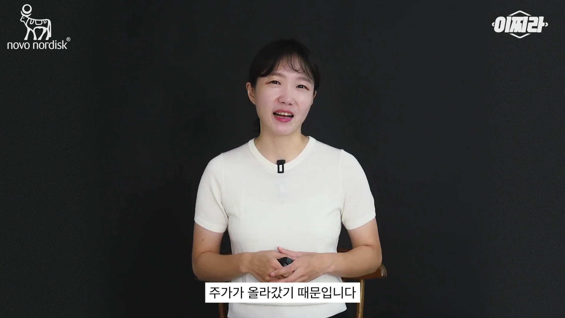 흰색 반팔 상의를 입은 여성이 검은색 배경 앞에서 이야기를 나누고 있으며, 화면 하단에는 '주가가 올라갔기 때문입니다'라는 자막이 표시되어 있습니다.