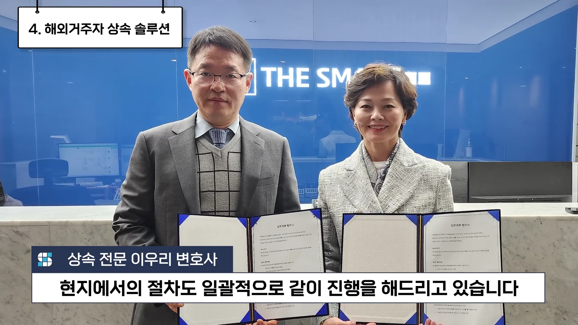 두 명의 중년 남녀가 사무실 배경으로 각각 업무제휴 협약서 문서를 들고 서 있는 모습