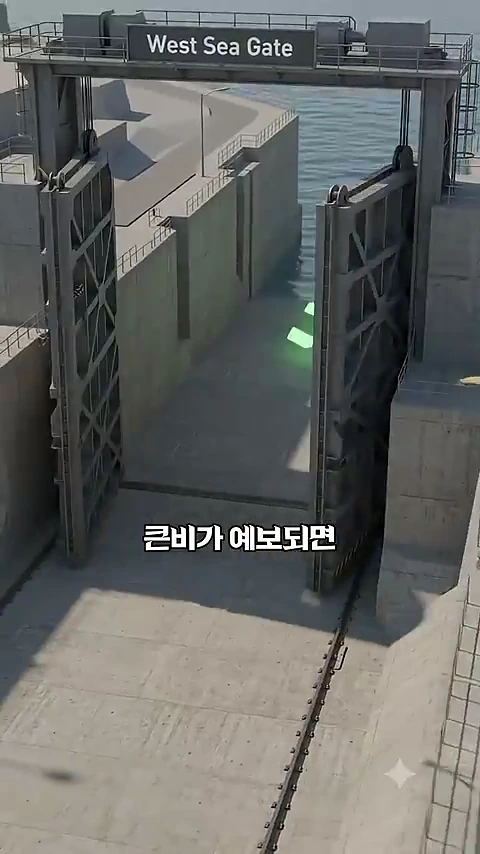 대형 철제 수문이 열려 있는 모습과 그 위에 적힌 West Sea Gate라는 영어 문구, 그리고 큰비가 예보되면이라는 자막이 겹쳐진 그래픽 화면