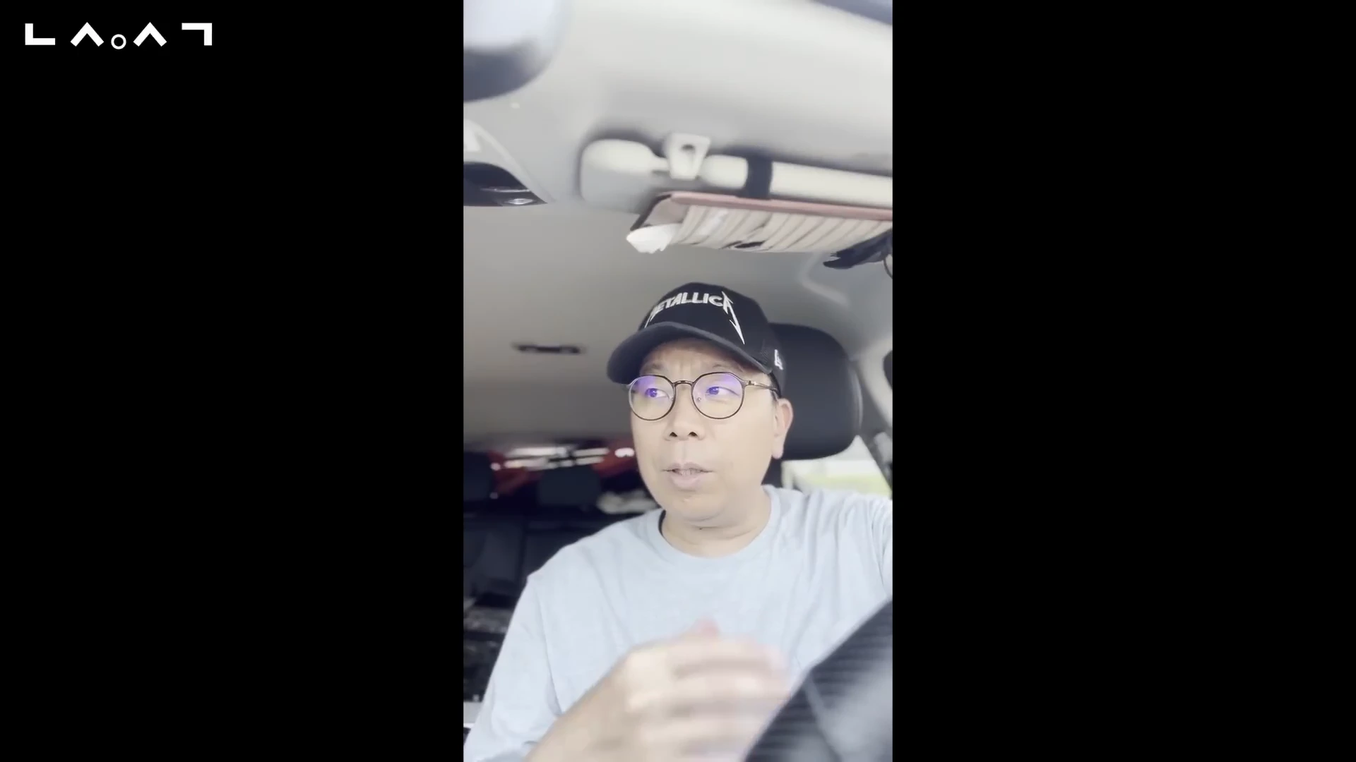 차량 운전석에 앉아 검은색 모자를 쓰고 안경을 쓴 남성이 카메라를 보며 이야기를 나누고 있다.