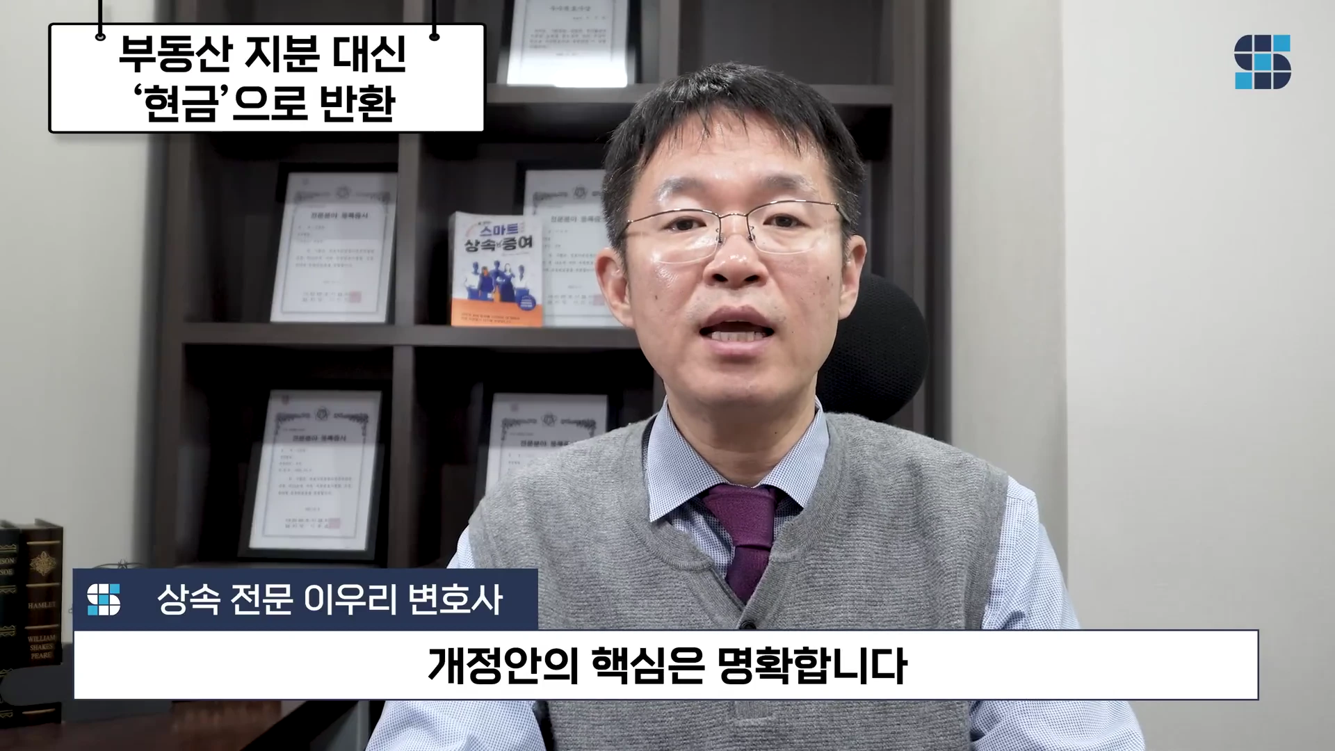 안경을 쓴 남성이 정장 조끼 차림으로 서재를 배경으로 서 있으며, 화면 상단에는 '부동산 지분 대신 현금으로 반환'이라는 텍스트가, 하단에는 '상속 전문 이우리 변호사'와 '개정안의 핵심은 명확합니다'라는 자막이 표시되어 있습니다.