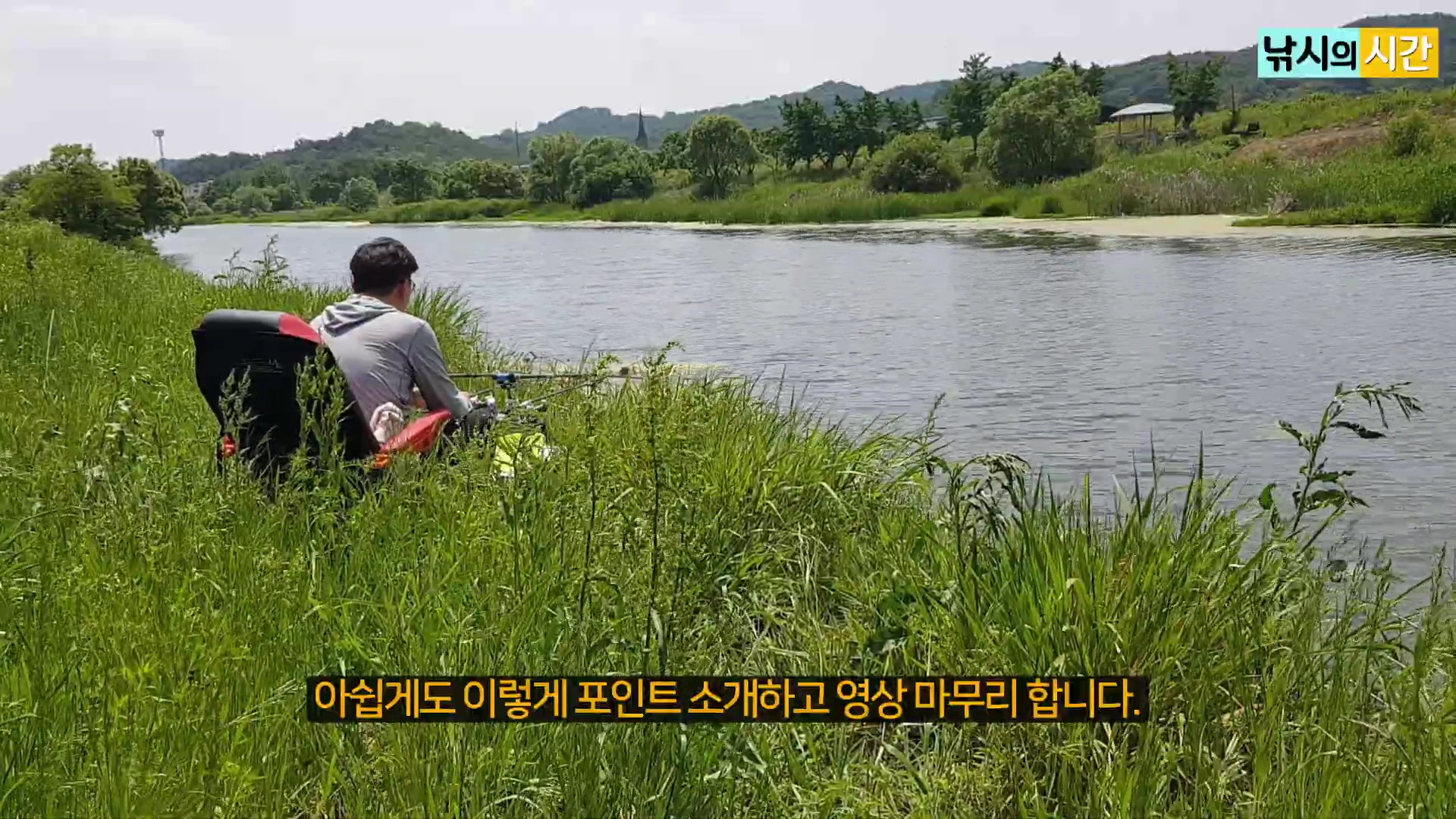 푸른 풀이 무성한 강둑에 의자를 놓고 앉아 낚싯대를 드리운 낚시꾼의 뒷모습.