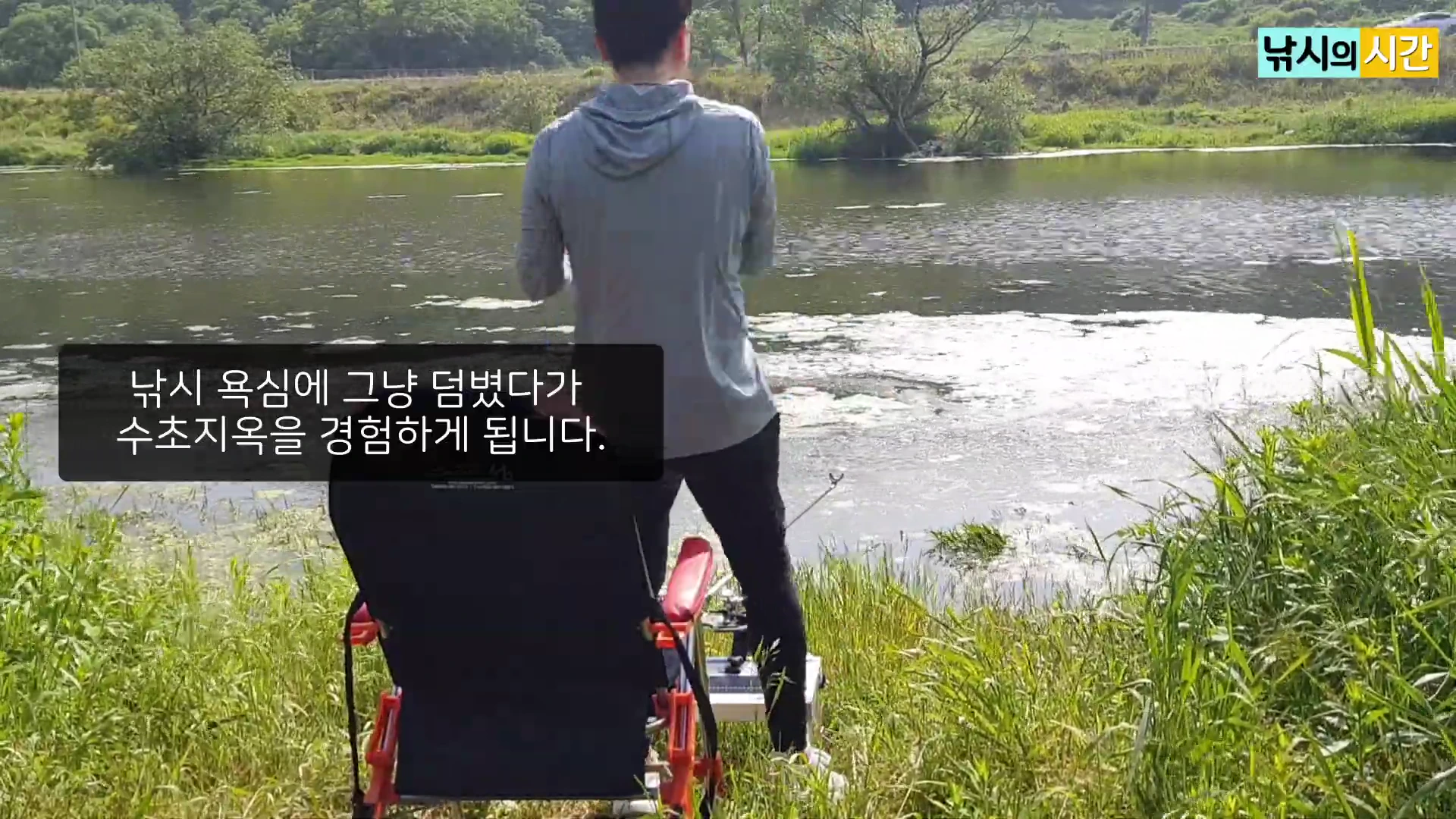 등 뒤로 낚시 의자에 앉아 강물을 바라보는 남성의 모습과 화면 중앙의 검은색 자막 상자.
