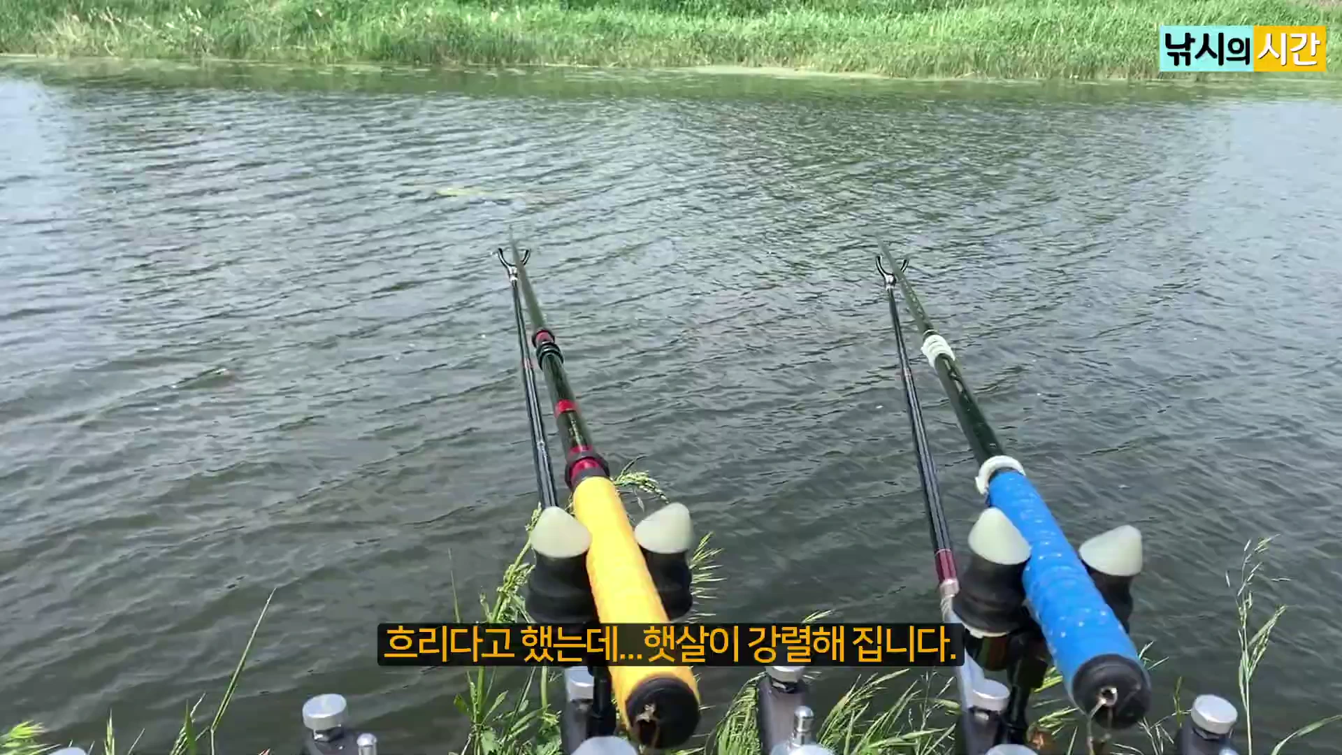 낚시터 물가에 설치된 두 개의 낚싯대와 낚시 받침대 모습