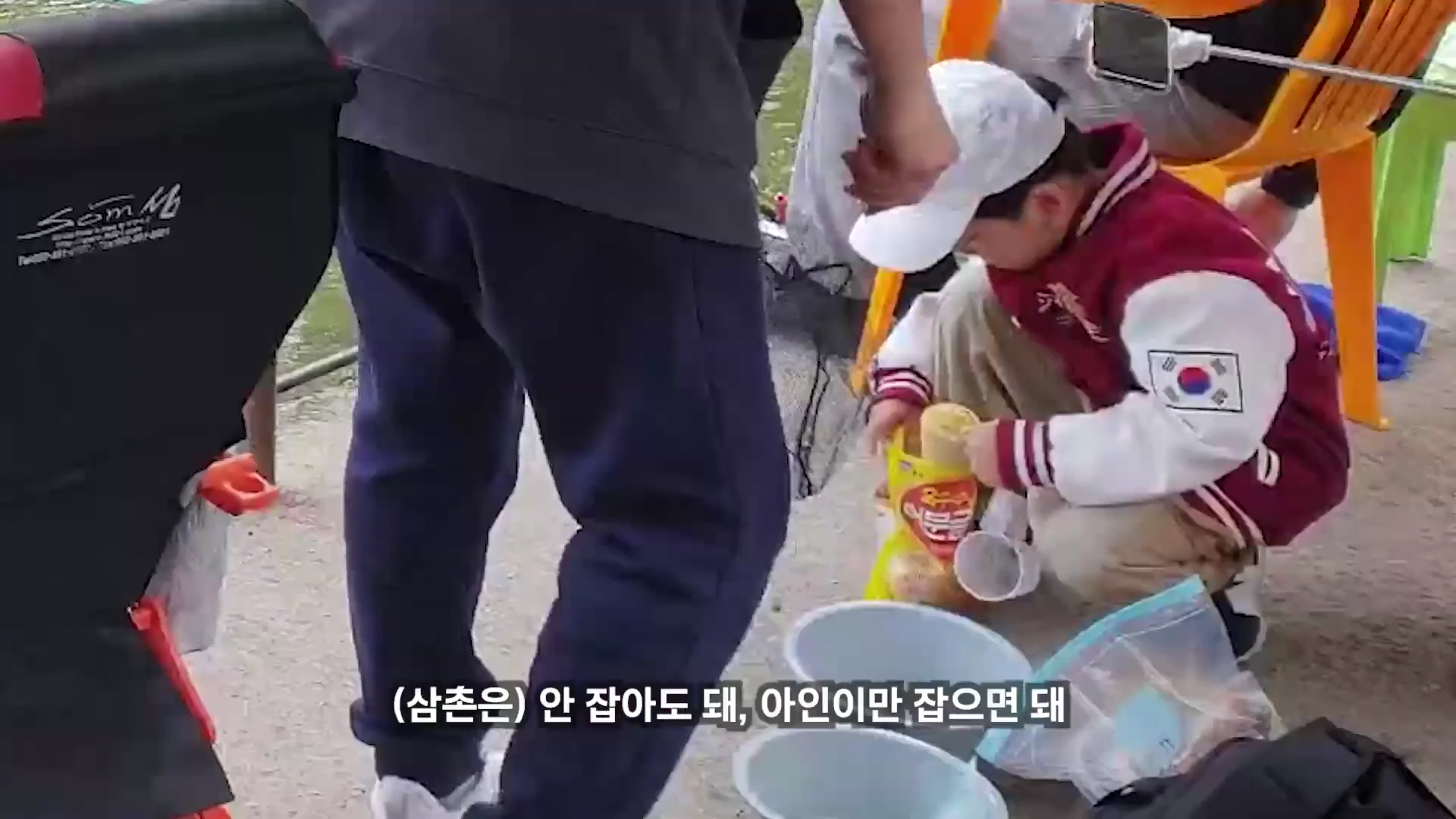 흰 모자를 쓴 어린이가 야외 낚시터에서 떡밥을 배합하고 있는 모습입니다.