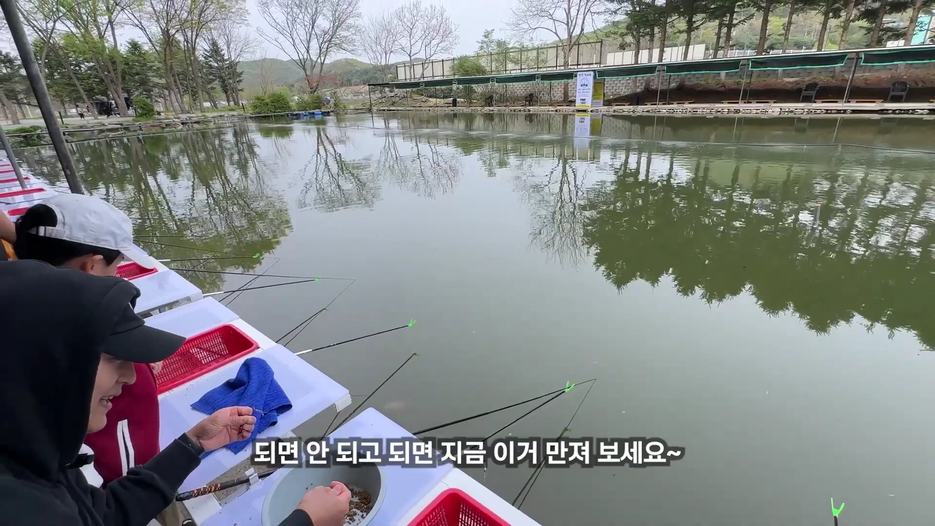 낚시터 수변 좌대에 앉은 사람들이 떡밥 미끼를 손으로 만지며 낚시 채비를 준비하는 모습