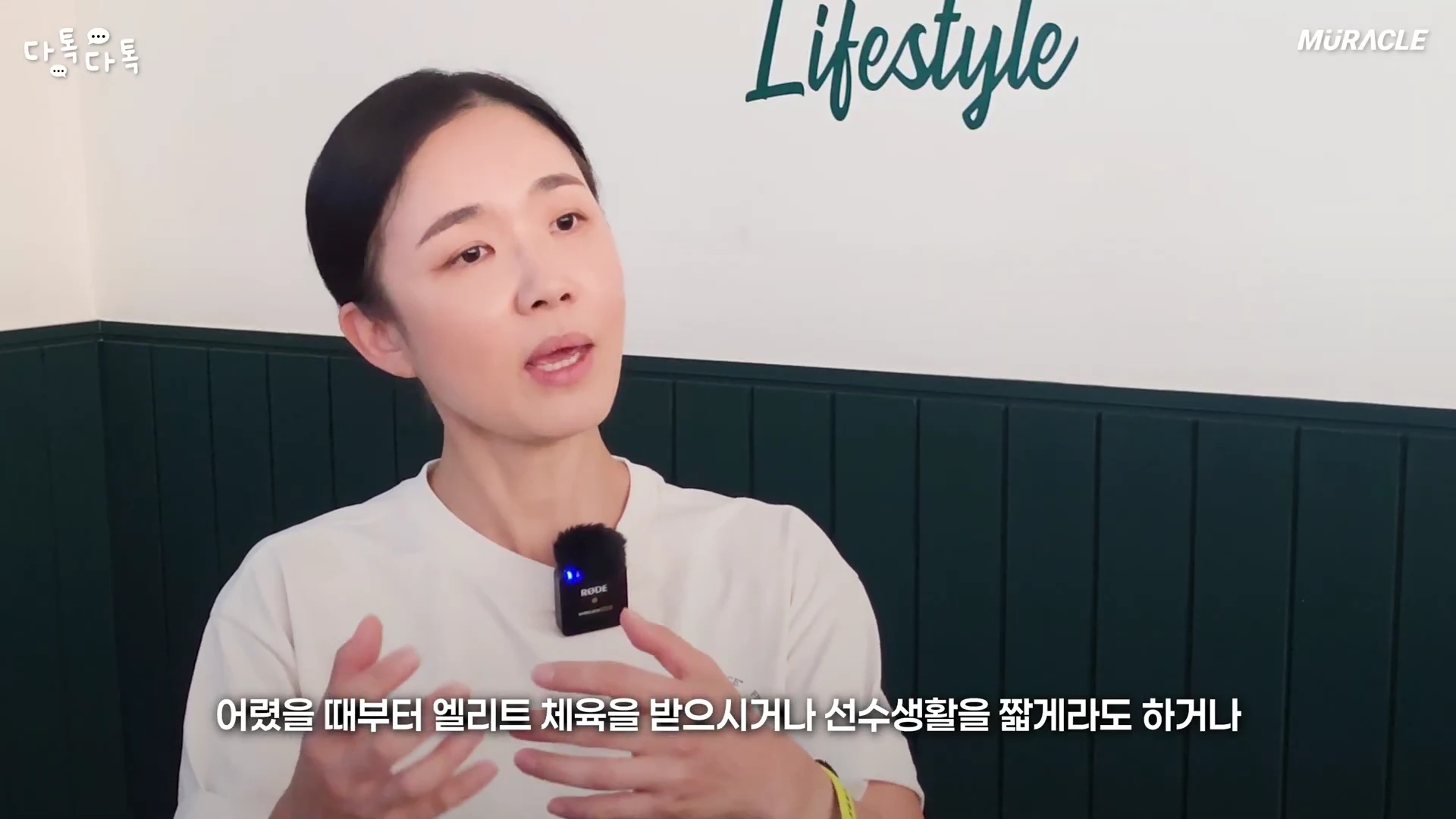 흰색 티셔츠를 입은 여성이 인터뷰하며 손동작으로 설명하고 있으며 화면 하단에는 자막이 떠 있습니다.