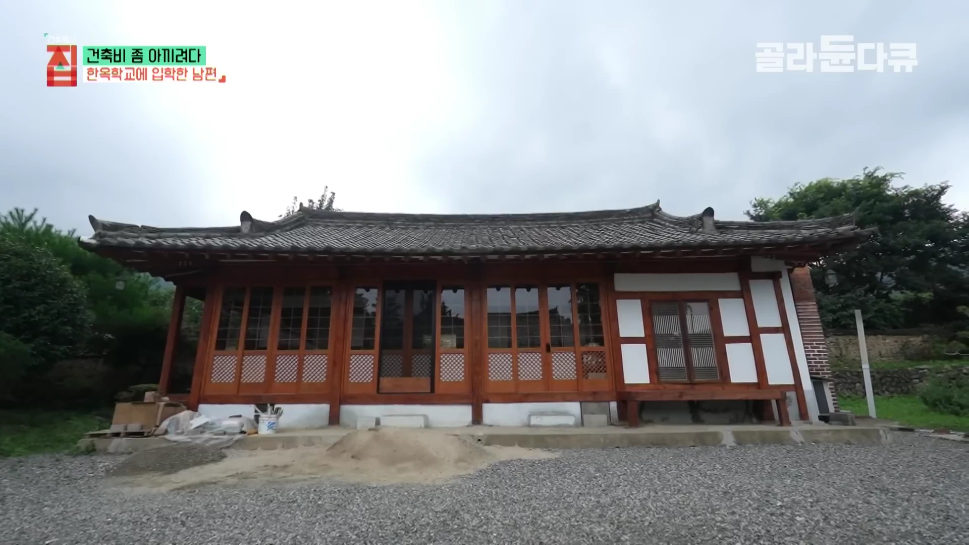 정면에서 바라본 80년 된 한옥의 모습으로, 어두운 기와 지붕 아래 갈색 목재 문틀과 정교한 문살이 조화를 이루고 있으며 왼쪽 상단에는 프로그램 제목과 에피소드 주제가 자막으로 표시되어 있습니다.