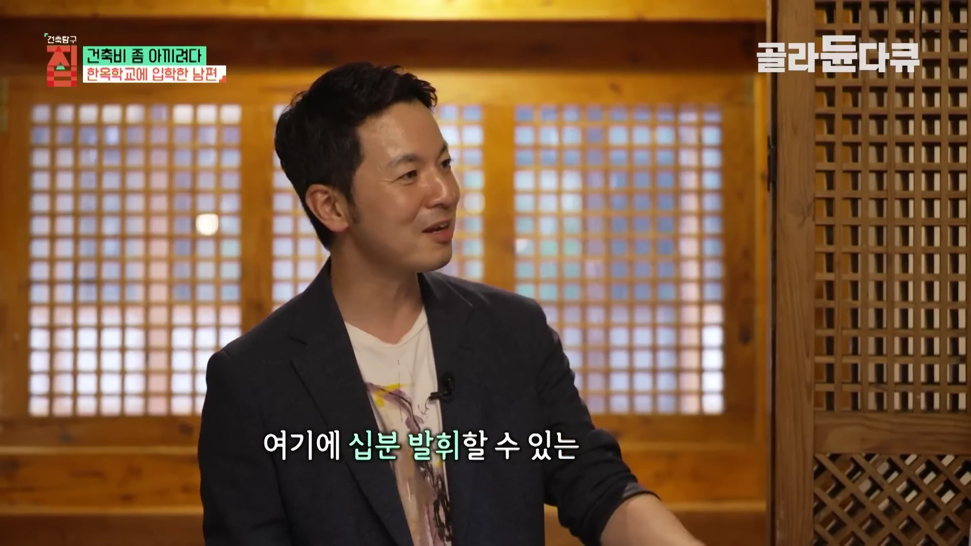 실내에서 한 남성이 인터뷰를 진행하고 있으며 배경에는 전통 목재 문살이 보입니다.
