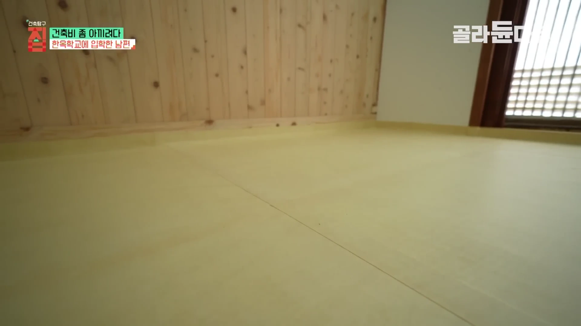 깔끔하게 단장된 한옥 방 내부의 평평한 바닥과 나무 벽면이 보이는 영상의 한 장면입니다.