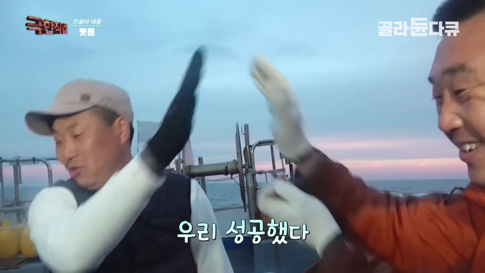 어선 갑판 위에서 장갑을 낀 두 남성이 서로 손바닥을 맞대며 하이파이브를 하고 있는 모습
