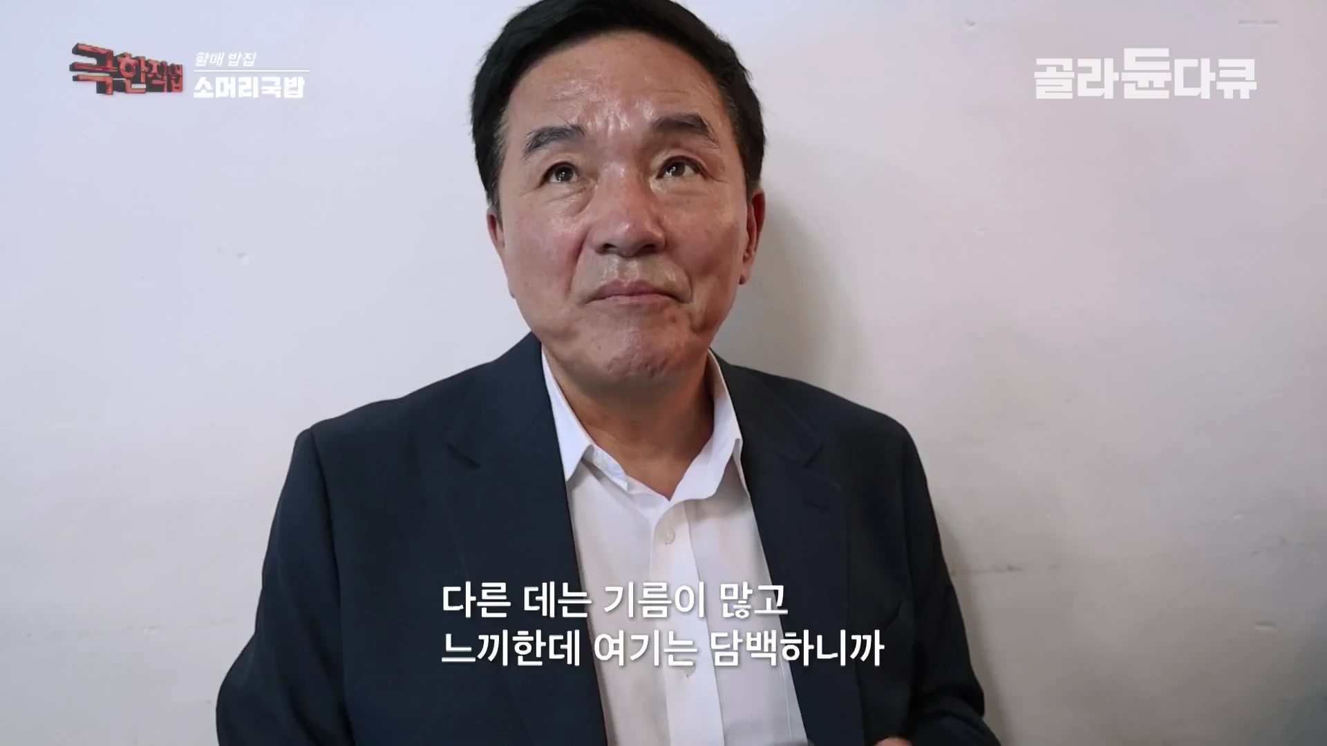 정장을 입은 중년 남성이 식당에서 인터뷰하며 이야기하는 모습이 담긴 화면이다.