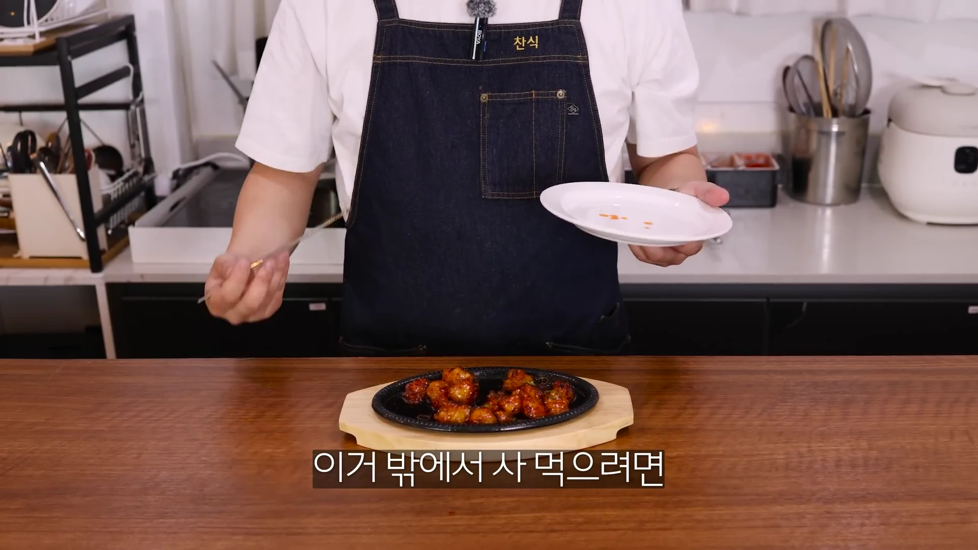 앞치마를 두른 요리사가 갓 조리한 매콤한 불대창 요리가 담긴 철판을 식탁 위에 내려놓고 있다.
