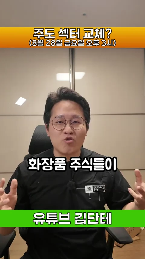 안경을 쓴 남성이 검은색 티셔츠를 입고 사무실 의자에 앉아 손을 들어 설명하며 이야기하고 있는 모습의 영상 캡처 화면이며, 화면 상단과 하단에는 노란색과 녹색 띠에 텍스트가 적혀 있다.