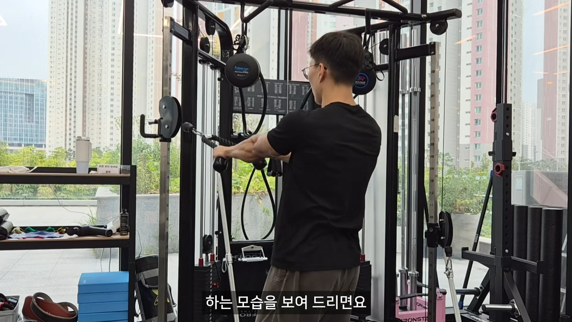 운동복 차림의 남성이 체육관에서 케이블 로프를 양손으로 잡고 페이스풀 동작을 수행하는 모습이다.
