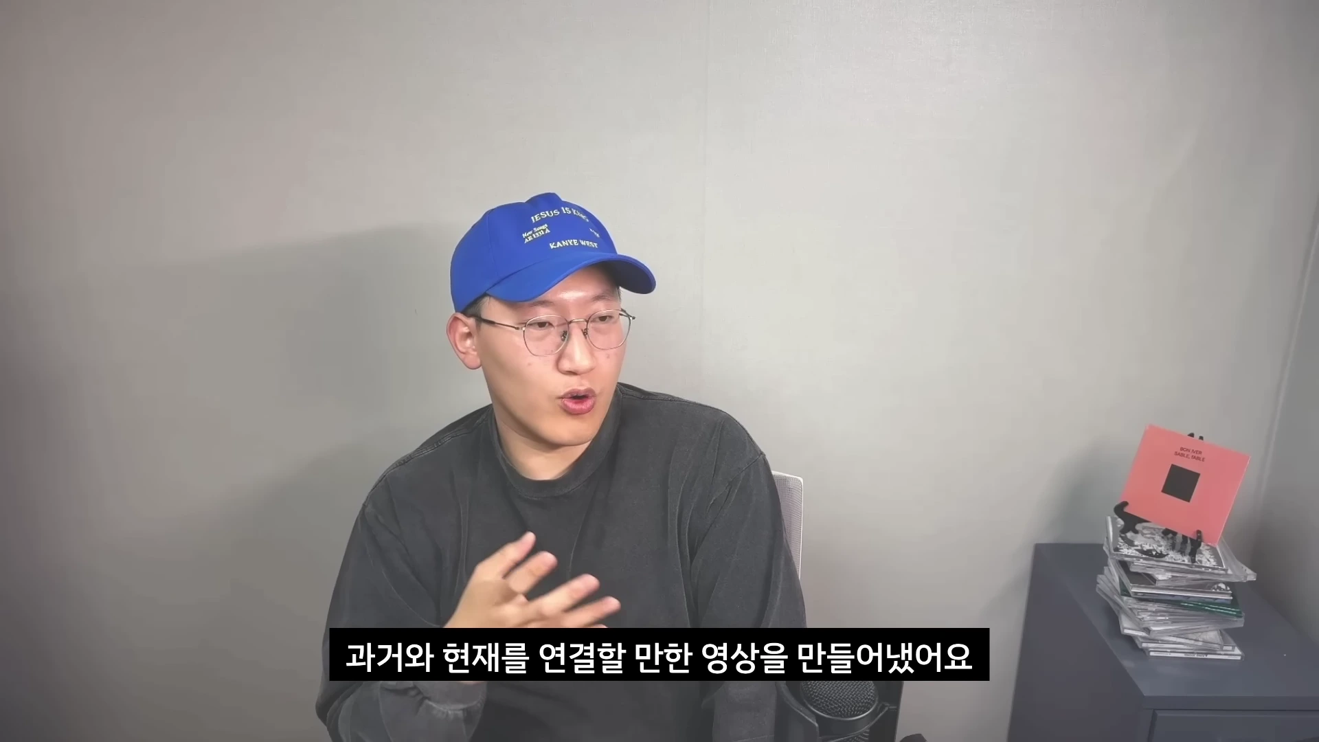 파란색 야구 모자와 안경을 착용한 남성이 회색 배경 앞에서 무언가 설명하며 이야기하고 있으며, 하단에는 한국어 자막이 표시된 영상 캡처 화면입니다.
