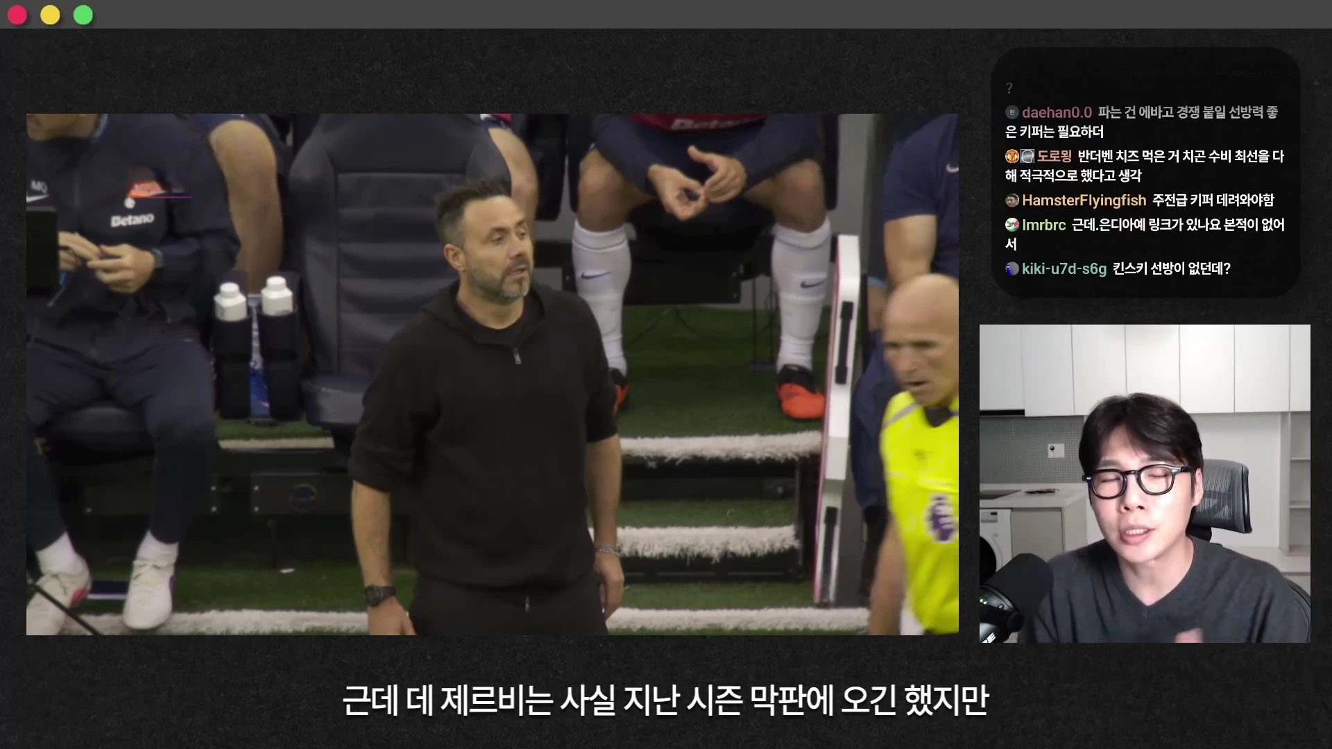 경기장 터치라인에서 검은 후드티를 입은 감독이 서 있고, 화면 하단 우측에는 안경을 쓴 남성이 마이크 앞에서 대화하는 모습이 담긴 화면입니다.