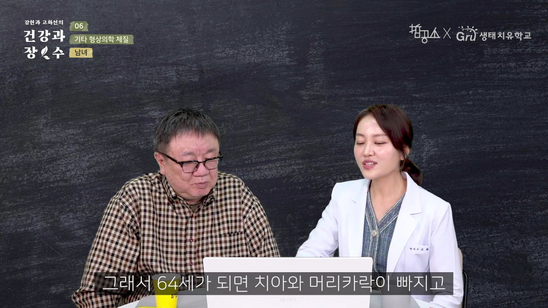 검은색 배경의 스튜디오에서 체크무늬 셔츠를 입은 중년 남성과 흰색 의사가운을 입은 여성이 책상을 사이에 두고 앉아 대화를 나누고 있으며, 화면 하단에는 자막이 삽입되어 있습니다.
