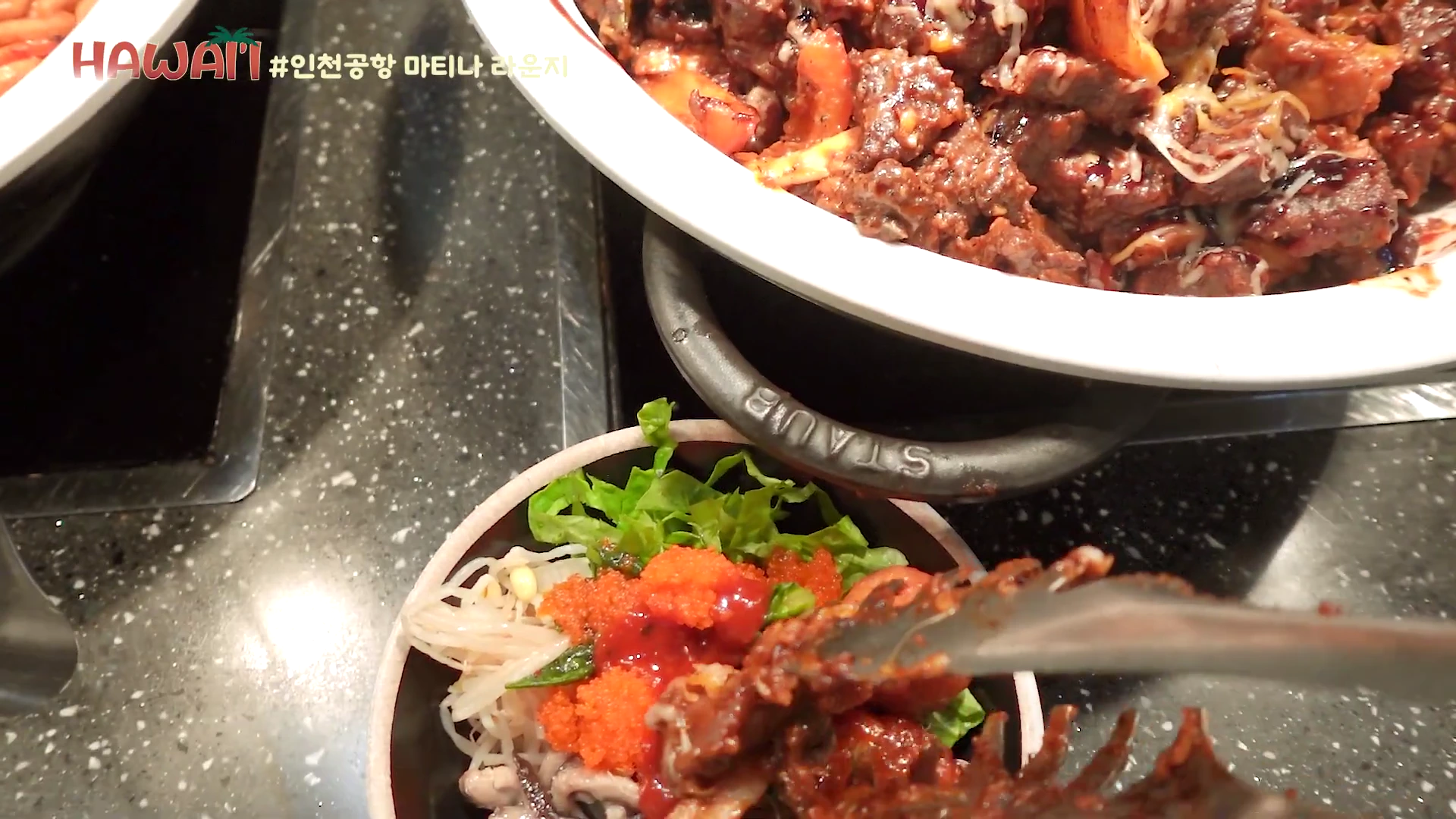 인천공항 라운지 뷔페 코너에서 집게로 요리를 접시에 담는 모습이 담긴 클로즈업 영상입니다.