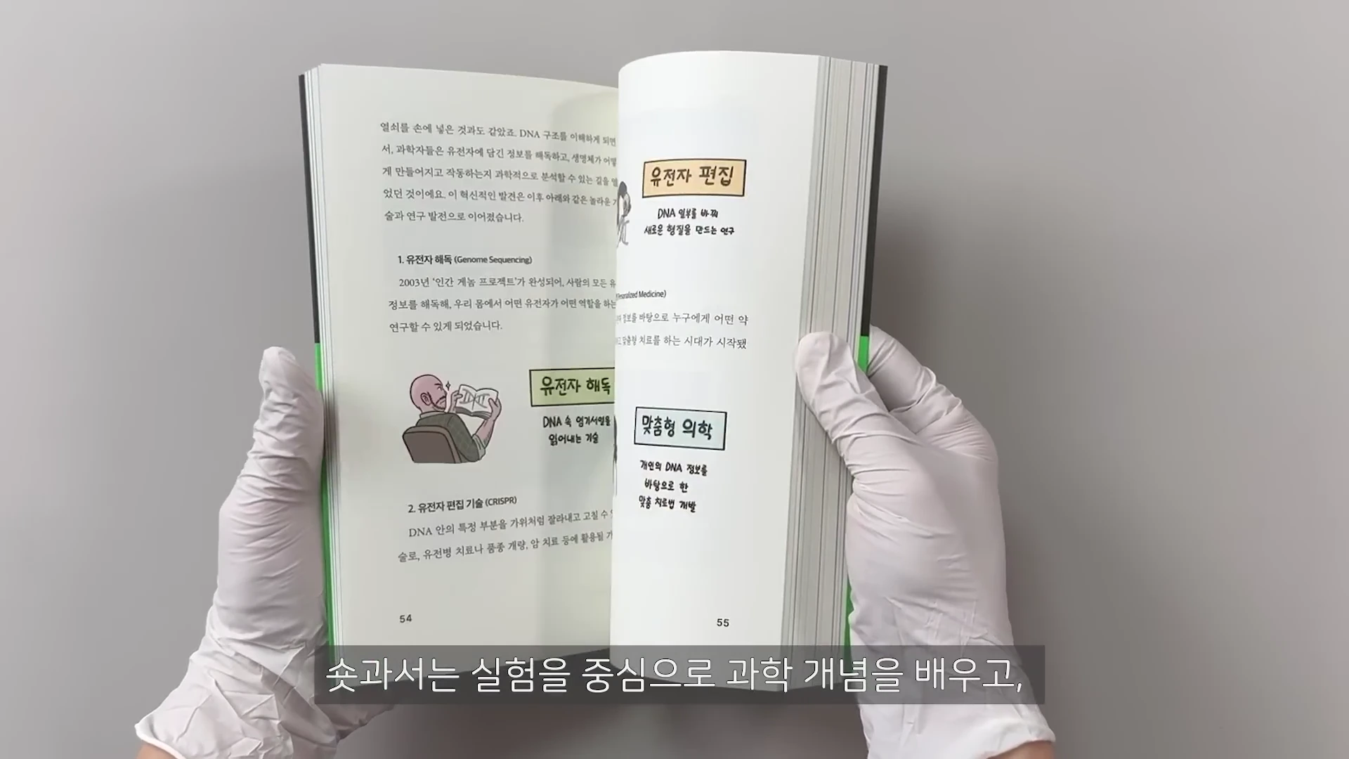 흰색 실험용 장갑을 낀 두 손이 과학 서적을 펼쳐 들고 있는 모습. 책에는 '유전자 편집', '유전자 해독', '맞춤형 의학'이라는 소제목과 함께 관련된 설명글과 삽화가 담겨 있음.