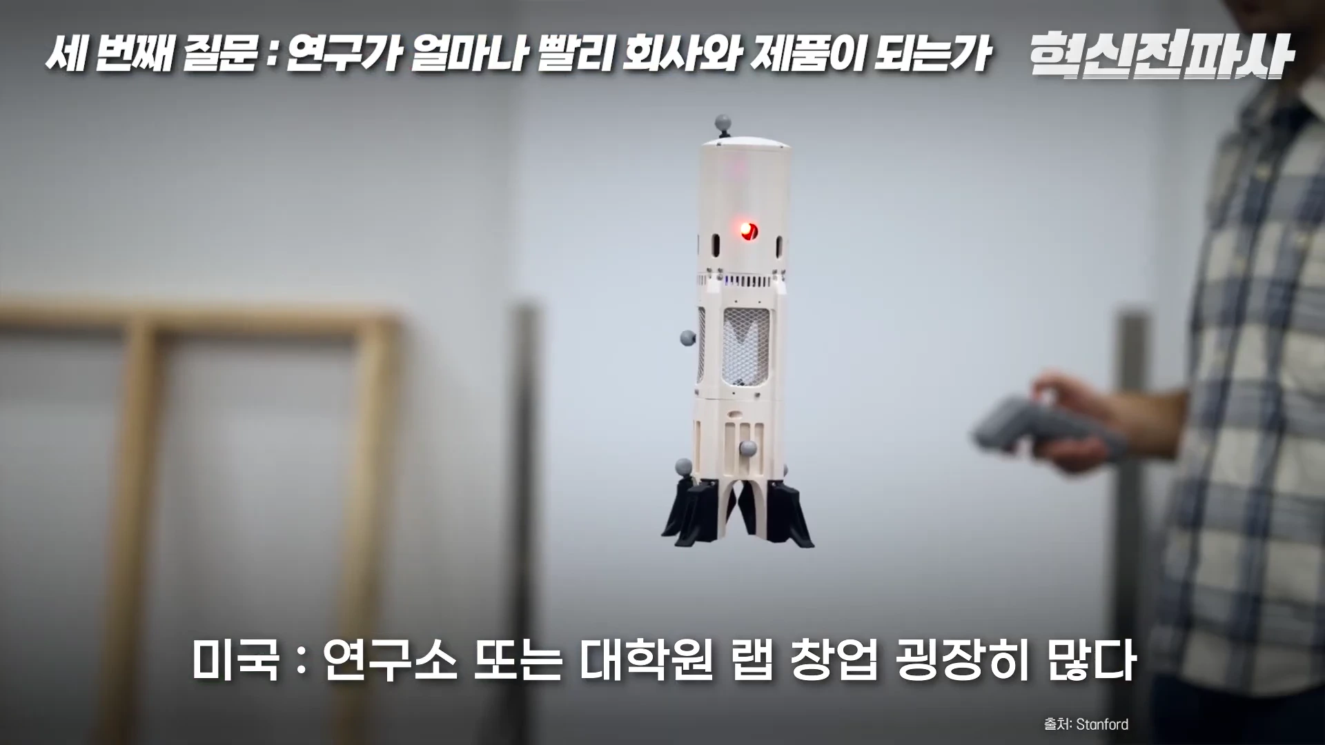 실내에서 사람이 손에 조종기를 든 채 공중에 떠 있는 원통형의 소형 로봇을 테스트하고 있는 모습이 담긴 영상 캡처 화면
