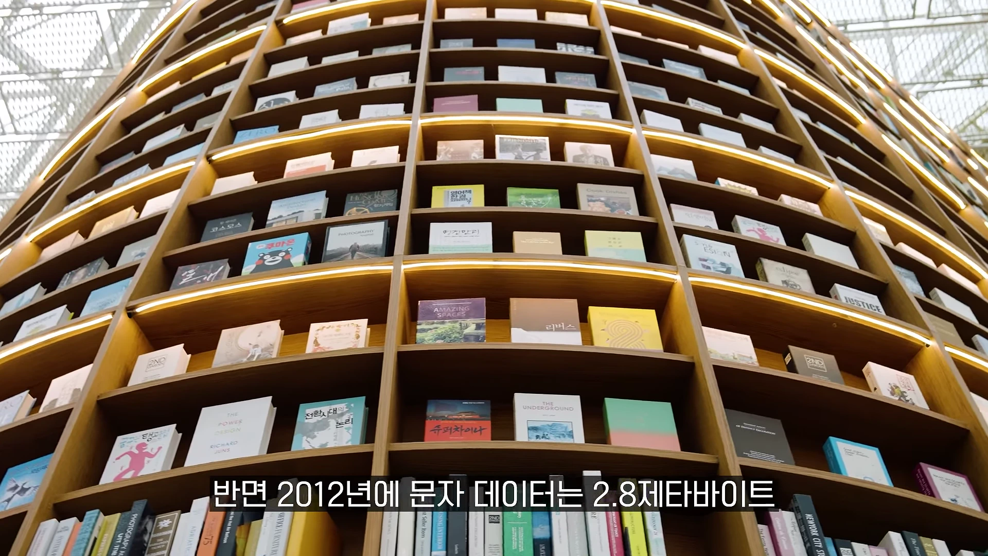 천장까지 닿을 듯 높게 쌓인 곡선형 대형 서가의 책장과 수많은 책이 꽂혀 있는 모습.