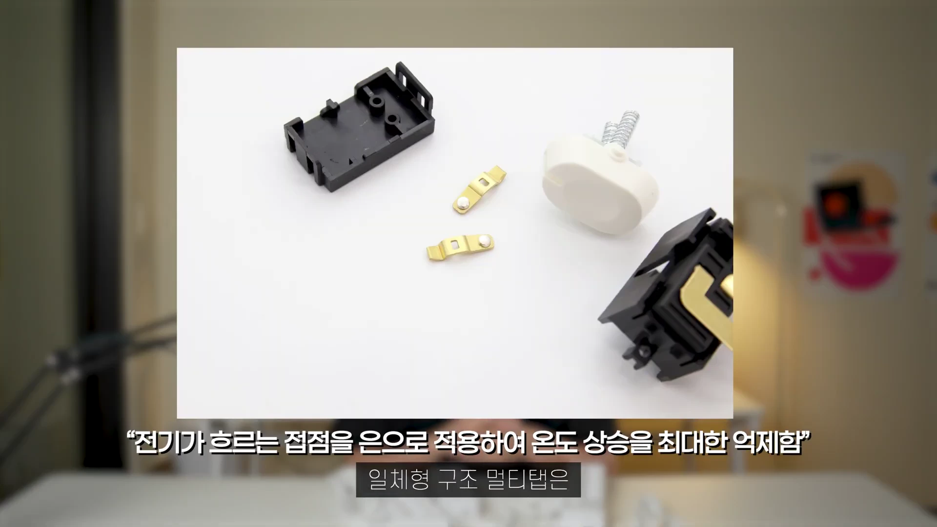 흰색 배경 위에 분해된 멀티탭 내부의 검은색 플라스틱 부품, 금속 단자, 그리고 흰색 스위치 부품이 나열되어 있다.