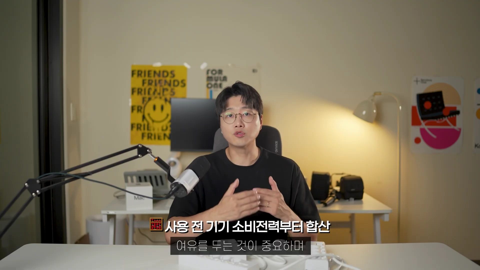안경을 쓴 남성이 마이크 앞에서 손동작을 하며 설명하고 있고, 화면 아래에는 '사용 전 기기 소비전력부터 합산'이라는 자막이 떠 있습니다.