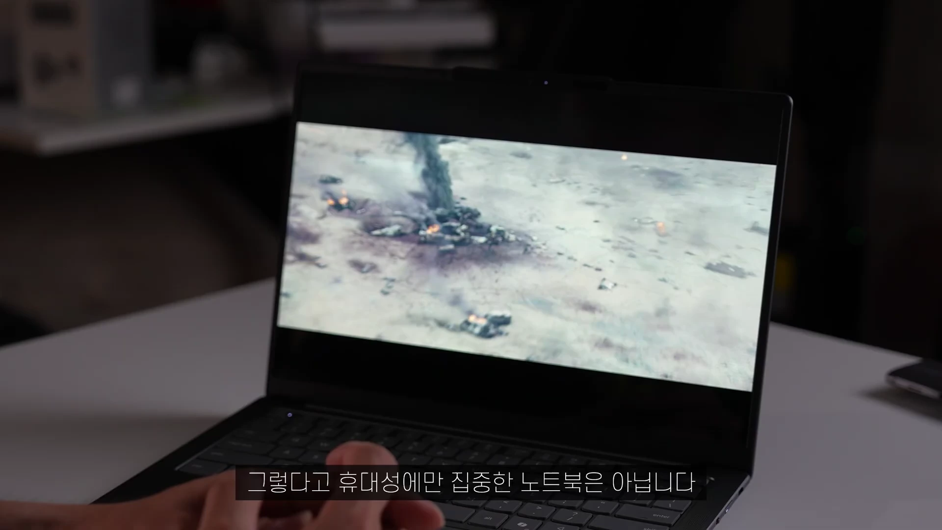 노트북 화면에 영화 영상이 재생되고 있으며, 하단에는 한국어 자막이 표시된 상태에서 사용자의 손이 노트북 앞에 놓여 있다.