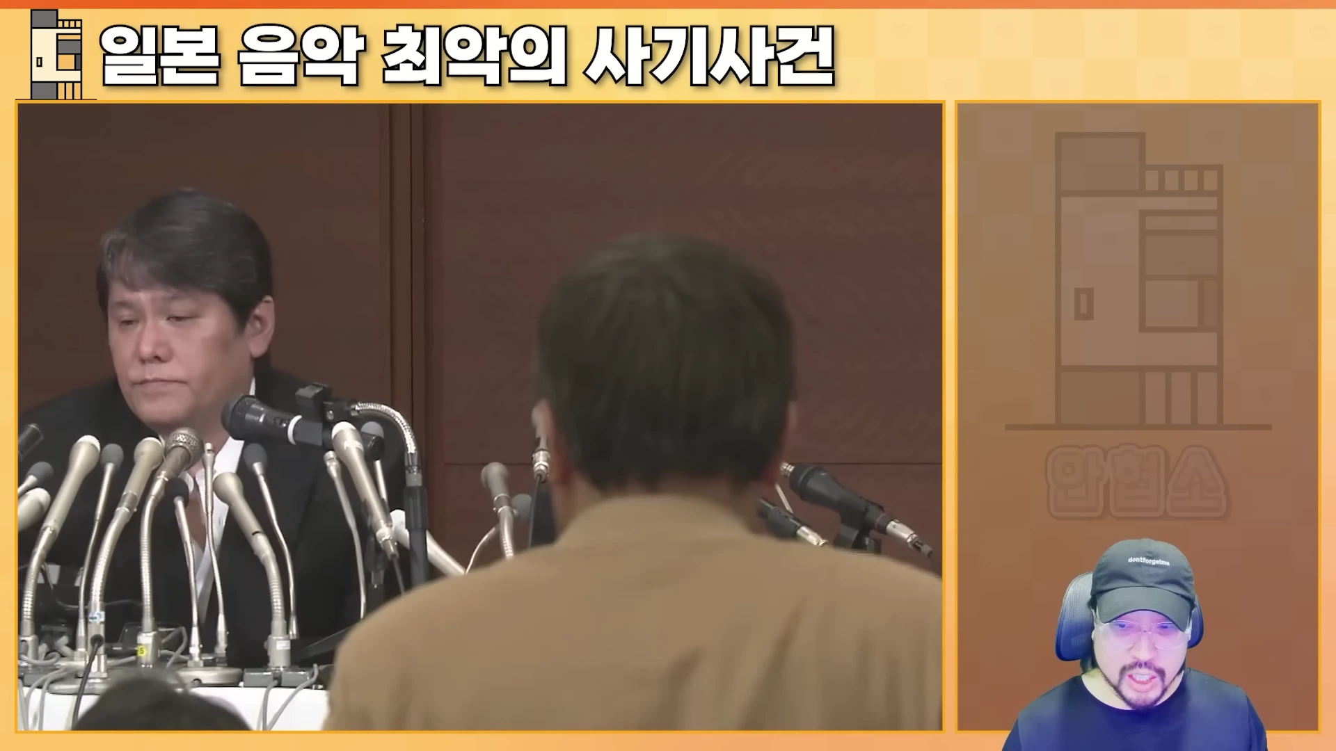 마이크가 여러 대 놓인 기자회견장에 앉아 있는 남성과 그 오른쪽 아래 화면에 모자를 쓴 남성이 등장하는 영상 프레임입니다.