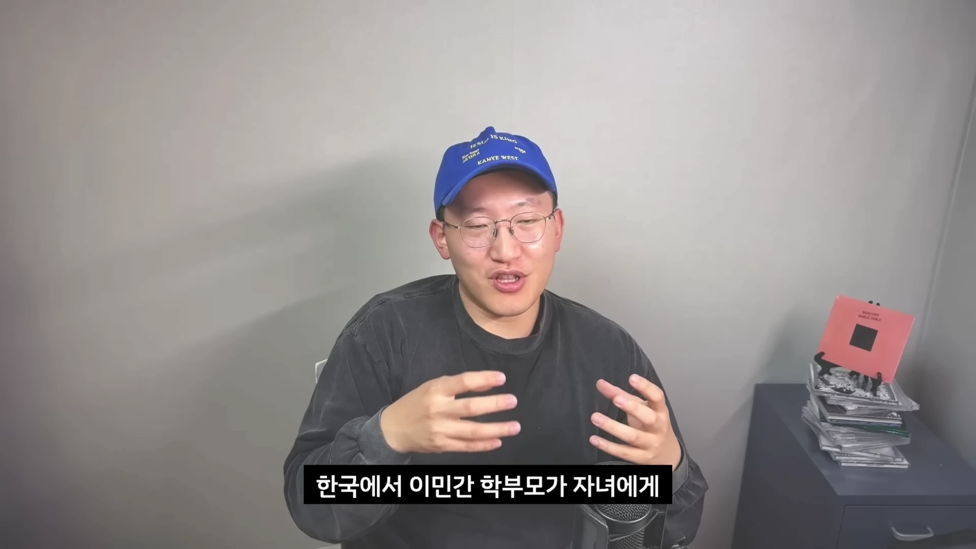 파란색 모자와 안경을 쓴 남성이 정면을 바라보며 손을 움직여 이야기하는 모습이 담긴 영상 캡처 화면.