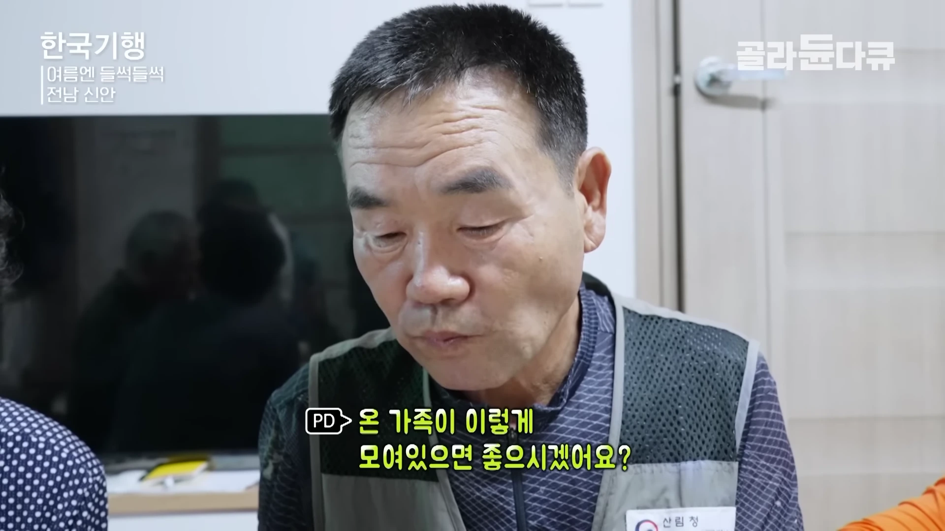 실내에서 작업 조끼를 입은 중년 남성이 식사하며 대화를 나누고 있는 모습이 담긴 방송 화면이다.