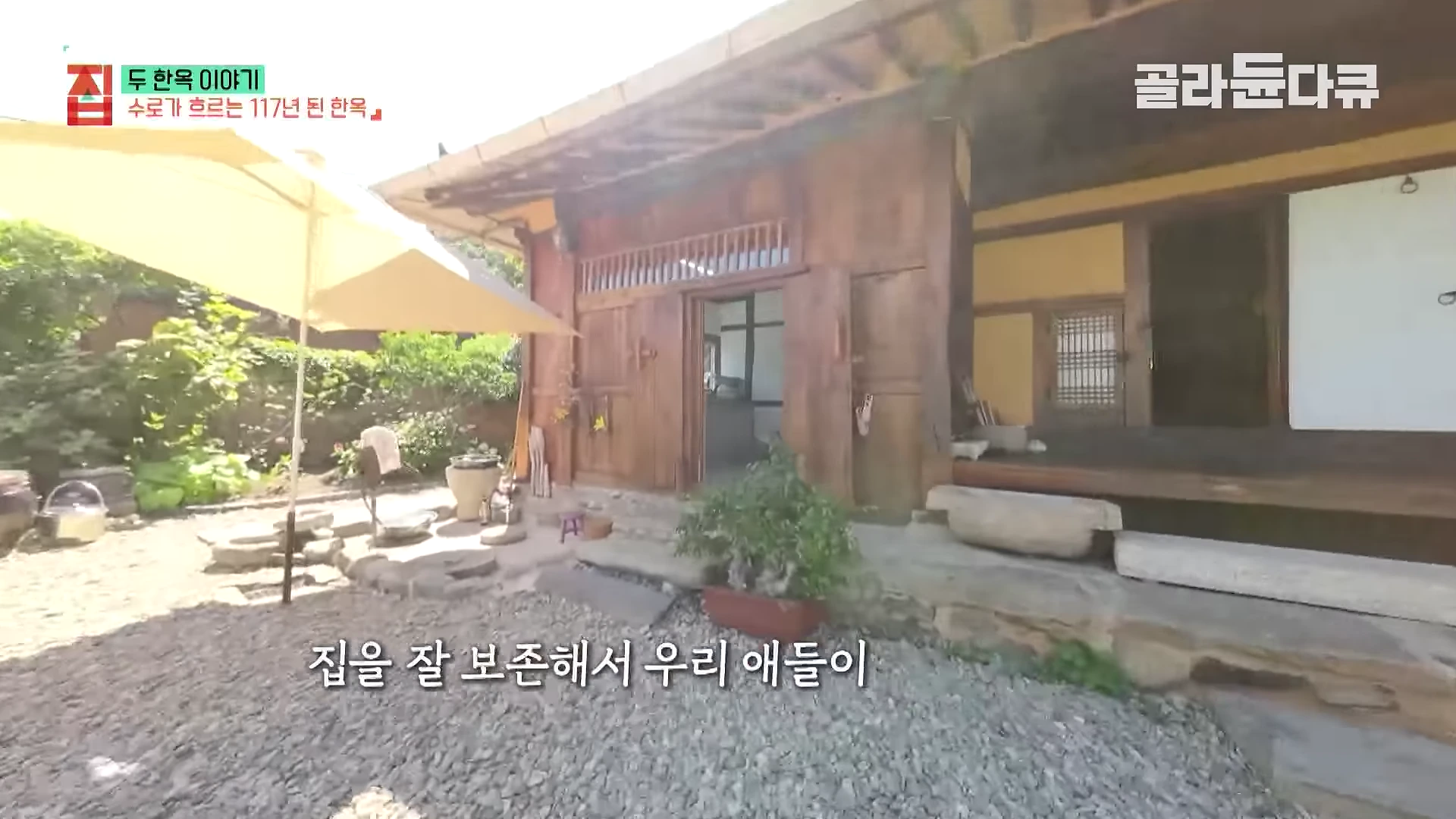 나무 기둥과 한식 문틀이 잘 보존된 117년 된 한옥 마당의 모습으로 대형 파라솔과 돌 바닥이 보입니다.