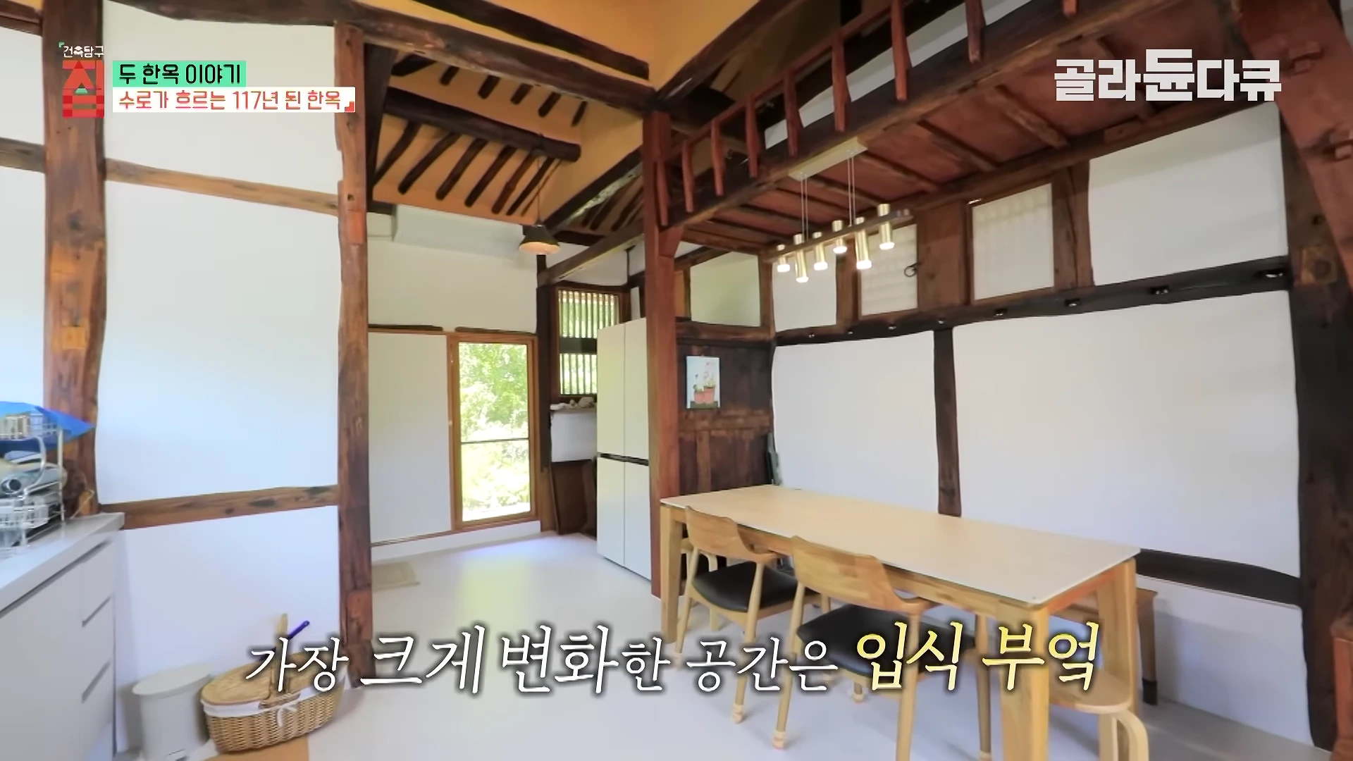 나무 기둥과 서까래가 드러난 한옥 내부 부엌 공간. 식탁과 현대식 가전제품이 놓여 있고 왼쪽으로 햇살이 들어오는 창문이 보인다.