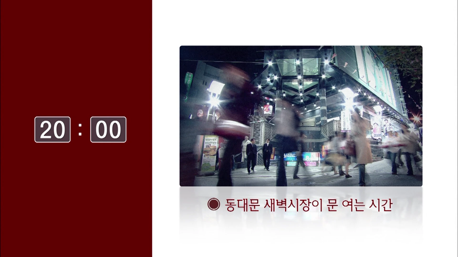 화면 왼쪽에 '20:00'이라는 디지털 시각이 표시되어 있고, 오른쪽에는 밤거리를 바쁘게 오가는 사람들의 모습이 담긴 영상이 재생되고 있습니다.