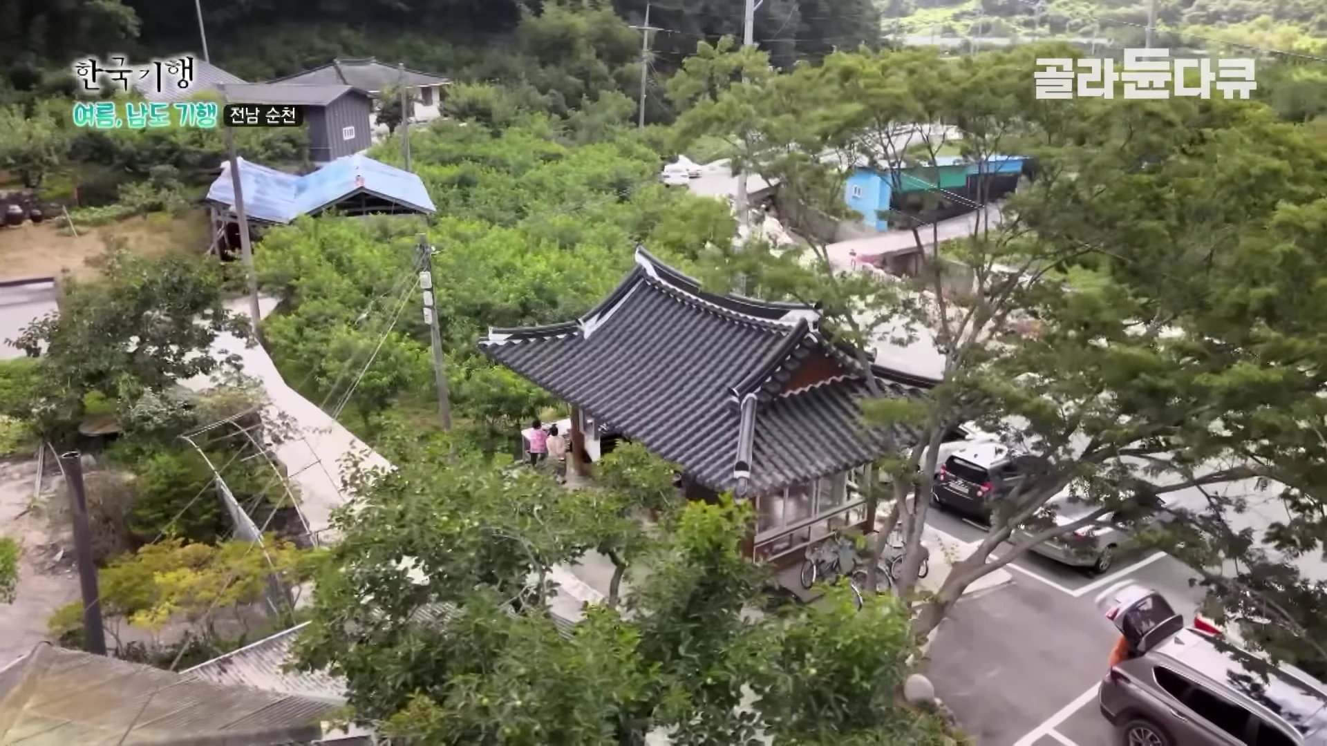 전남 순천의 한 시골 마을을 위에서 내려다본 풍경으로, 기와지붕이 얹힌 정자와 그 주변에 조성된 텃밭과 주차된 차량들이 보인다.