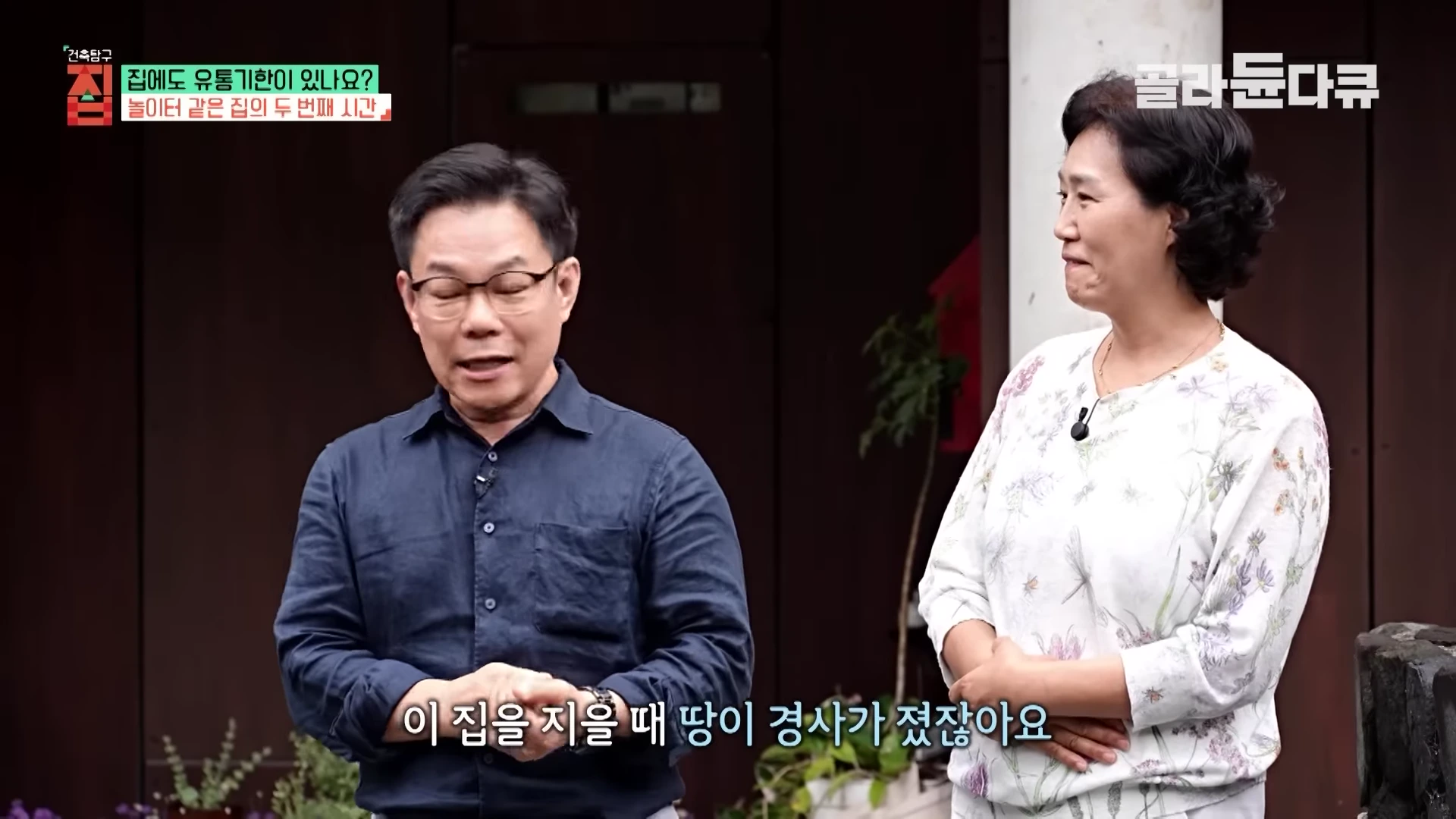 안경을 쓴 남성 건축가와 밝은색 블라우스를 입은 여성이 야외에서 대화를 나누고 있으며, 화면 상단에는 '건축탐구 집' 프로그램 자막이 표시되어 있습니다.