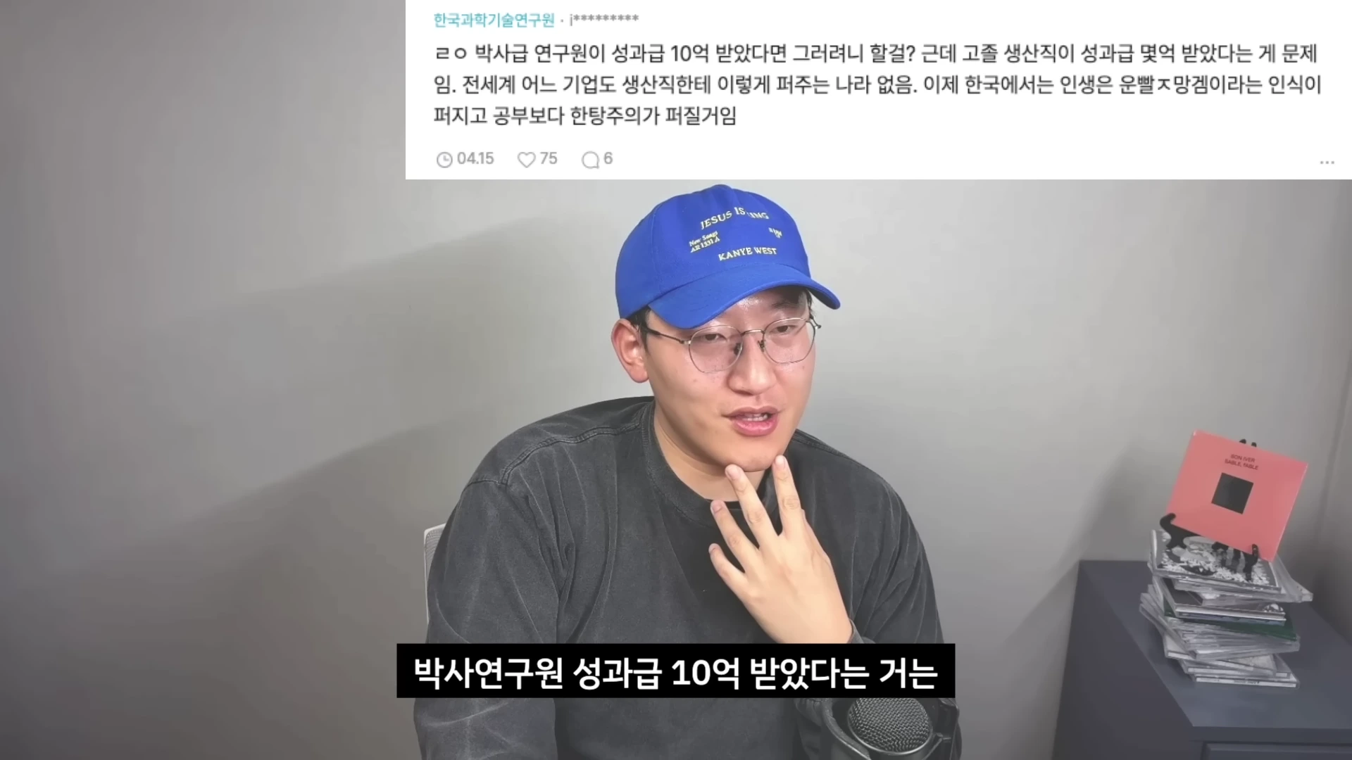 파란색 야구 모자를 쓴 안경 낀 남성이 카메라를 보며 말을 하고 있고, 그 위로 블라인드 커뮤니티의 댓글 내용을 담은 캡처 화면이 배치되어 있습니다.