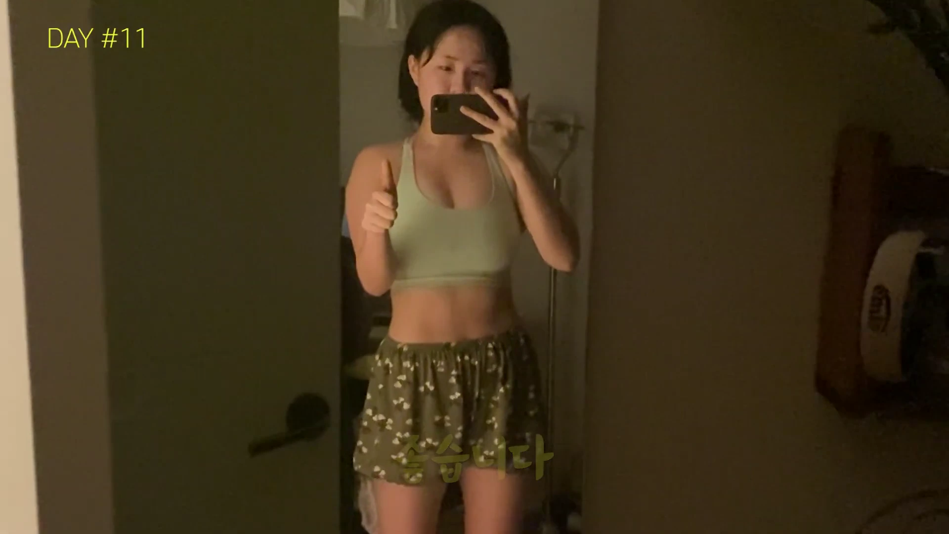 운동복 차림의 여성이 거울을 보며 엄지를 치켜세우고 있는 모습으로, 화면 왼쪽 상단에 'DAY #11'이라는 문구가 적혀 있습니다.
