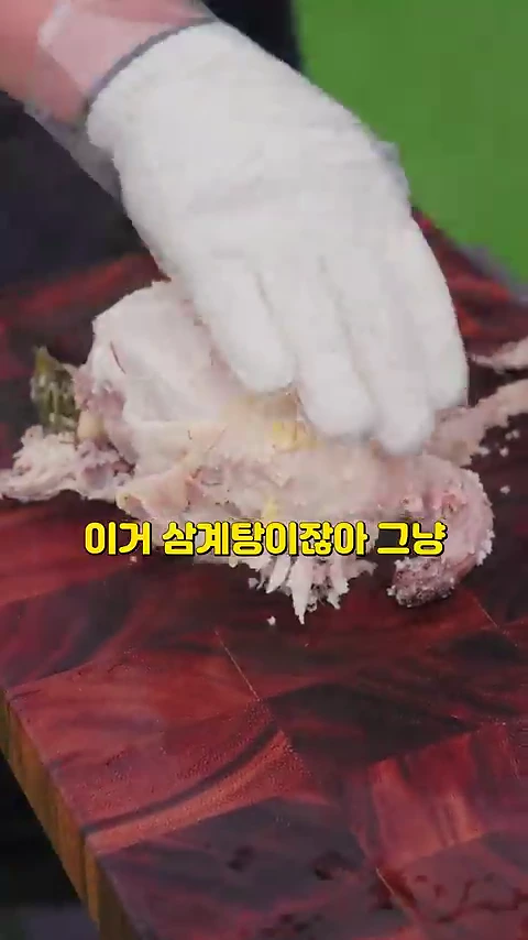 흰 장갑을 낀 손이 조리된 닭고기를 누르고 있으며, 화면 중앙에는 '이거 삼계탕이잖아 그냥'이라는 노란색 자막이 배치되어 있다.